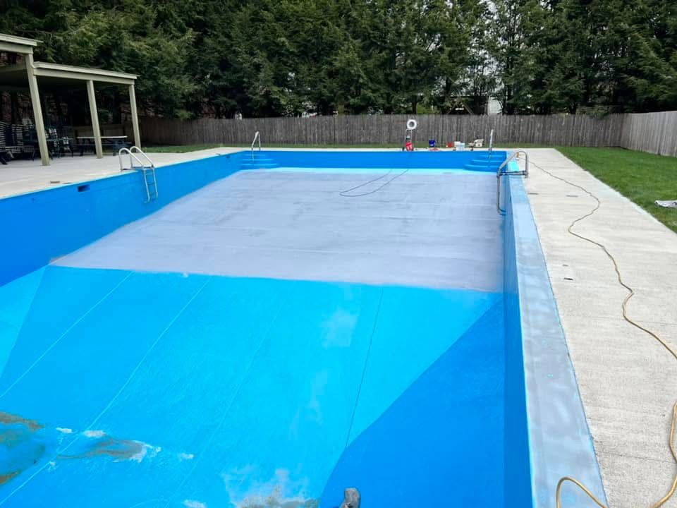 A blue swimming pool is being painted in a backyard.