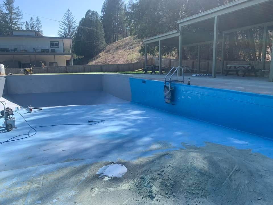An empty swimming pool with a house in the background