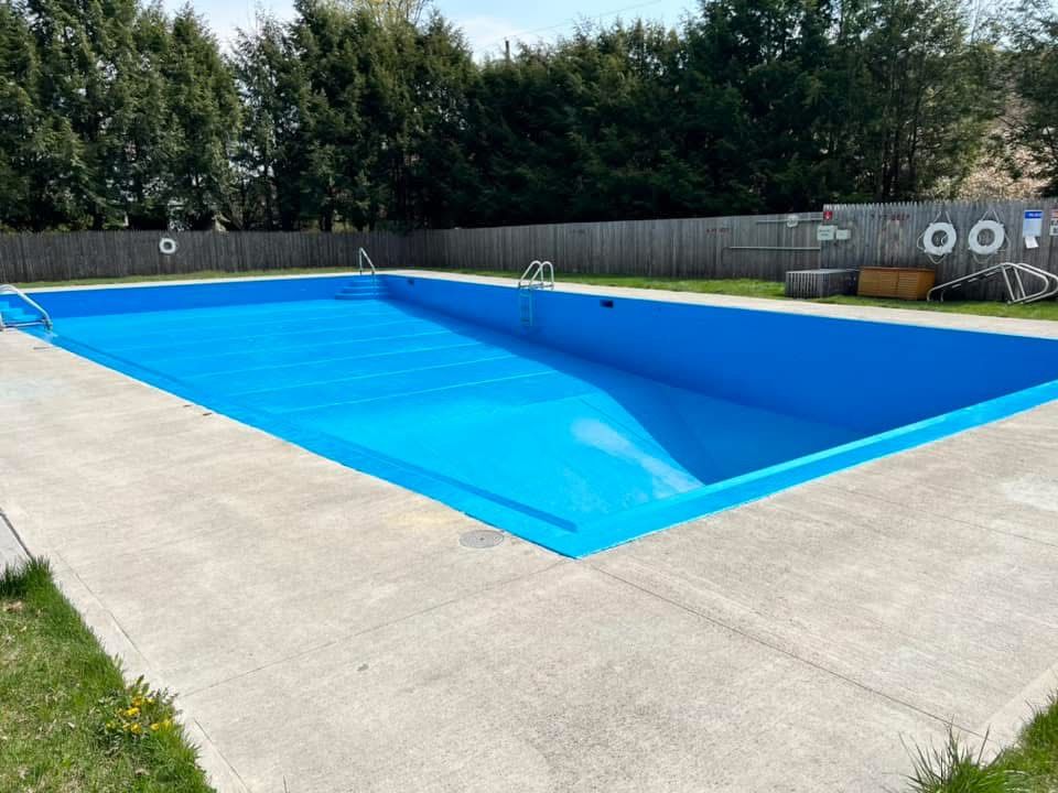 A large blue swimming pool with a wooden fence surrounding it