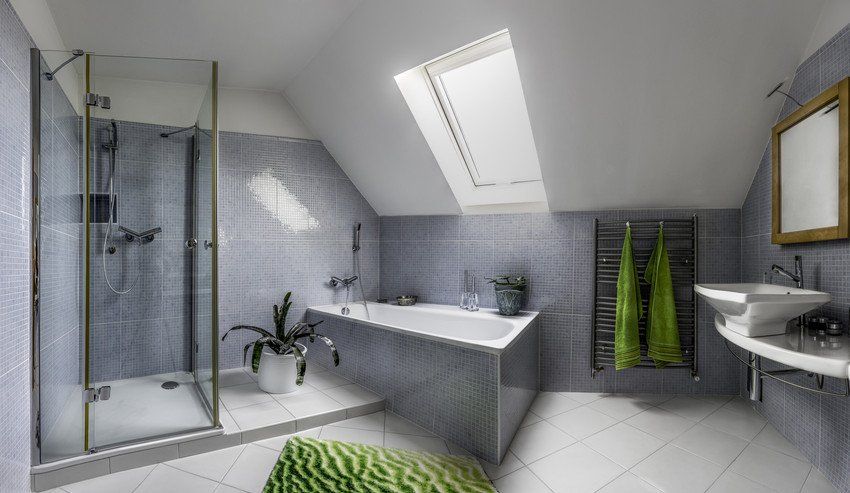 Modern bathroom in cool style with glass shower and bathtub in the attic of a house