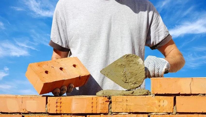 bricklayer laying bricks to make a wall