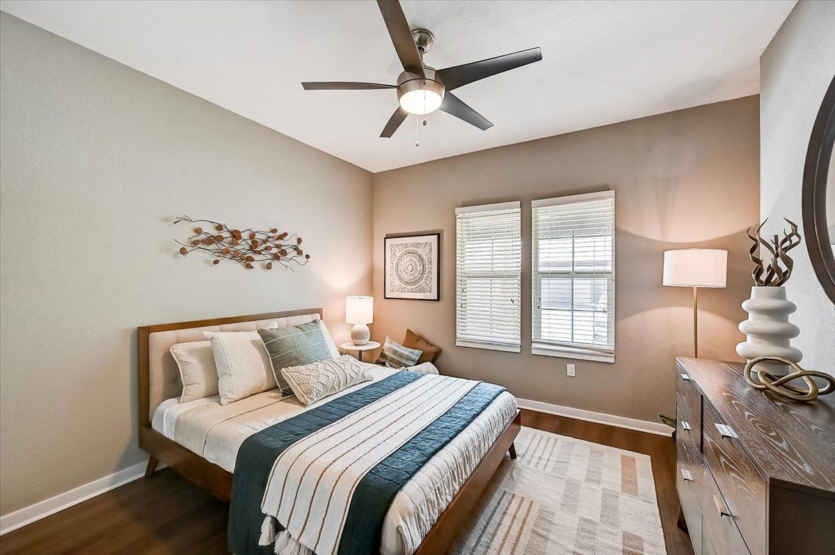 apartment bedroom with modern furnishings, hardwood flooring, and a ceiling fan