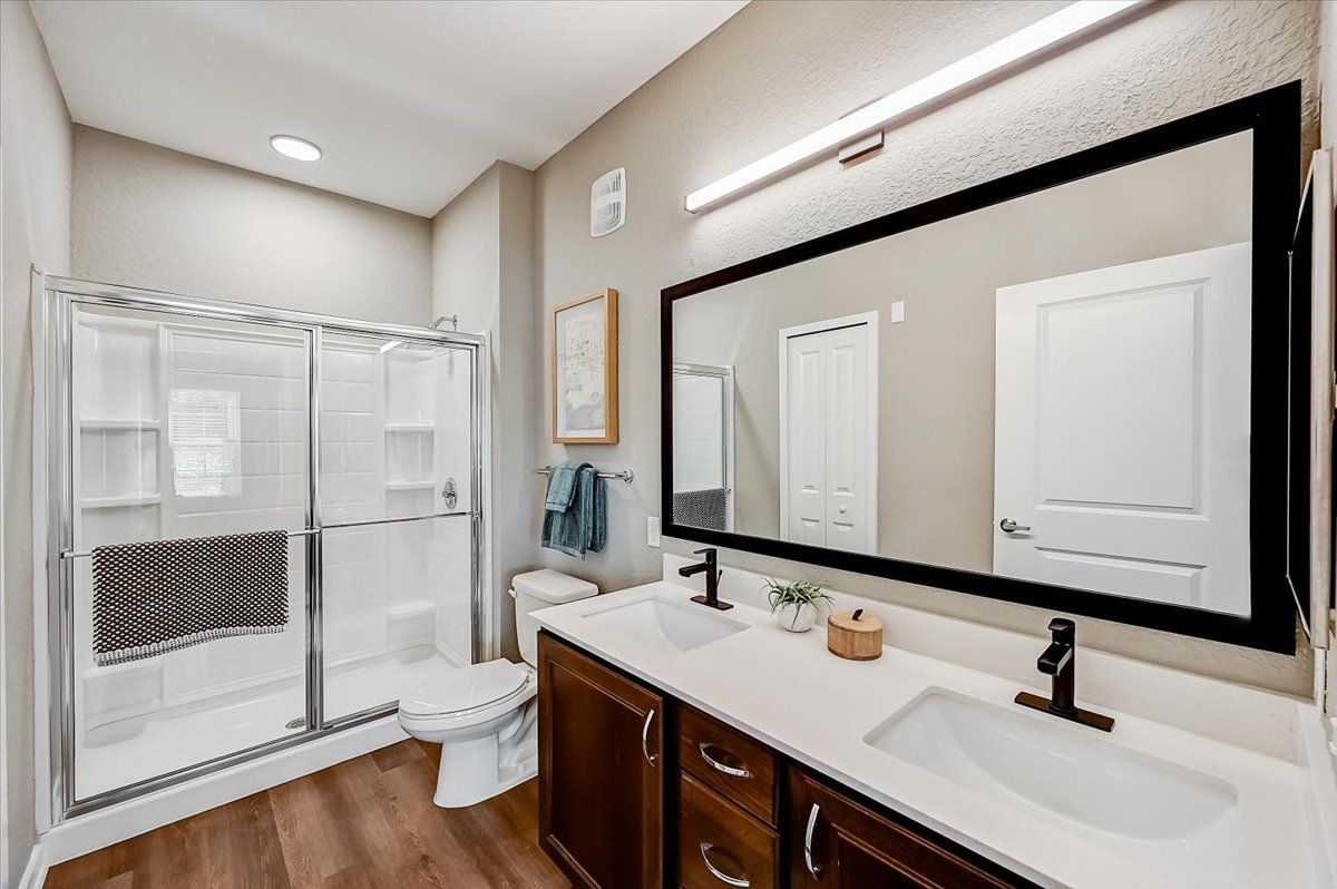 bathroom with a double vanity, large mirror, and walk-in shower