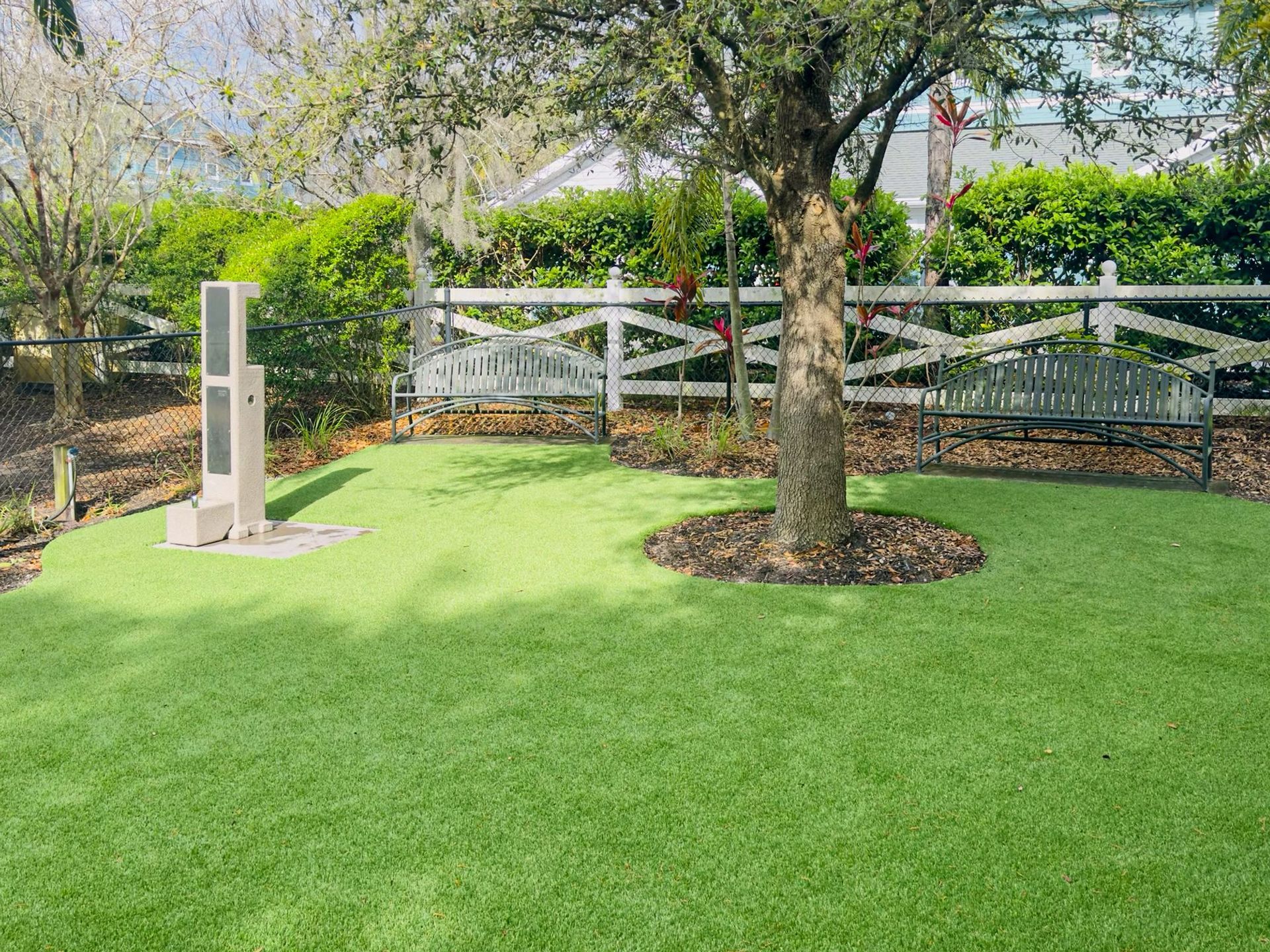 fenced-in dog park with bench seating and a water fountain