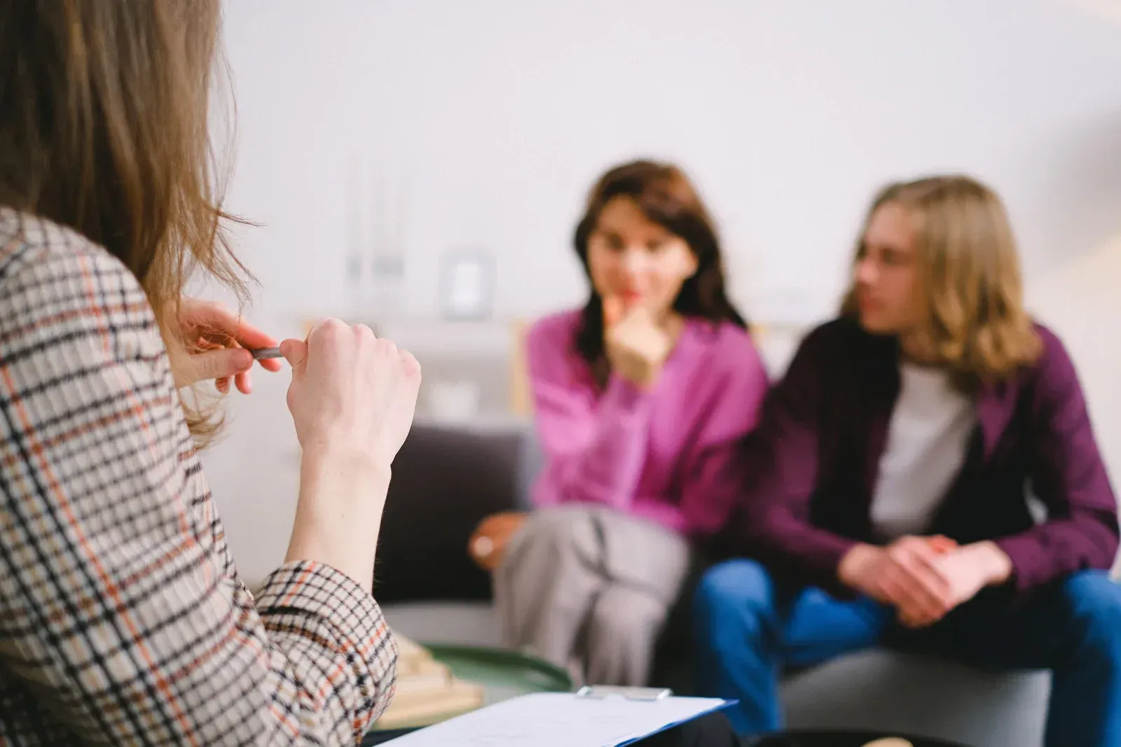 A woman is talking to a couple sitting on a couch.