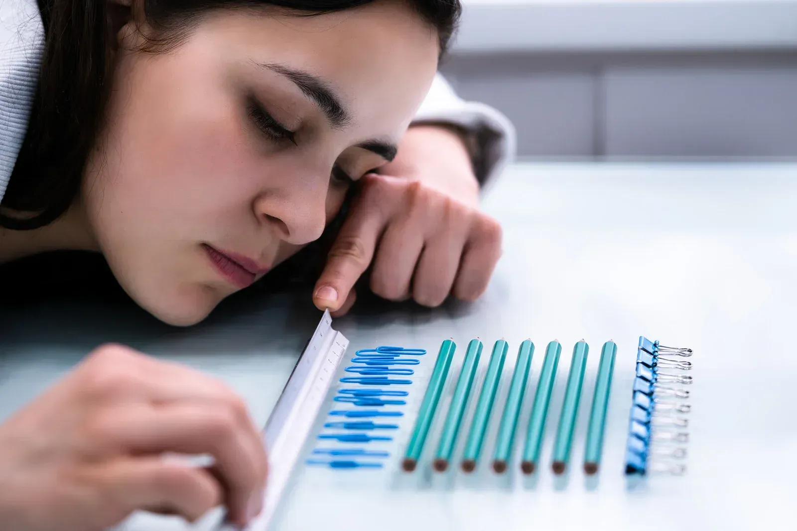 A woman is laying on a table with a bunch of pencils on it.