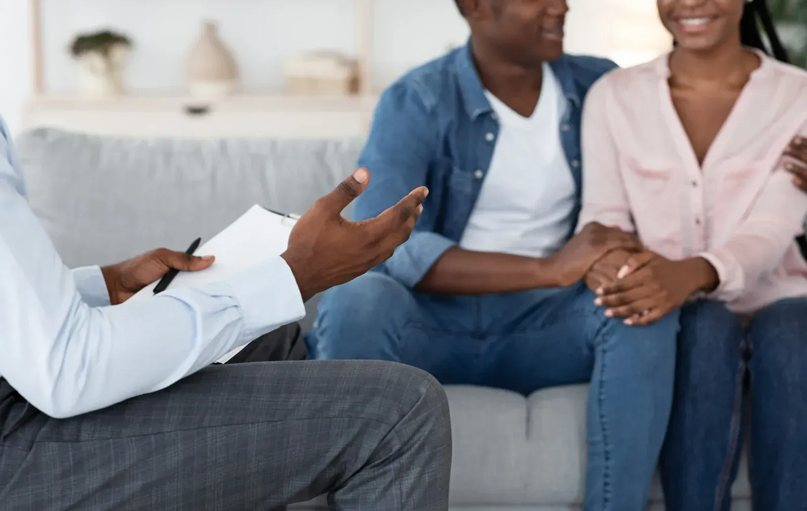 A man is sitting on a couch talking to a couple.