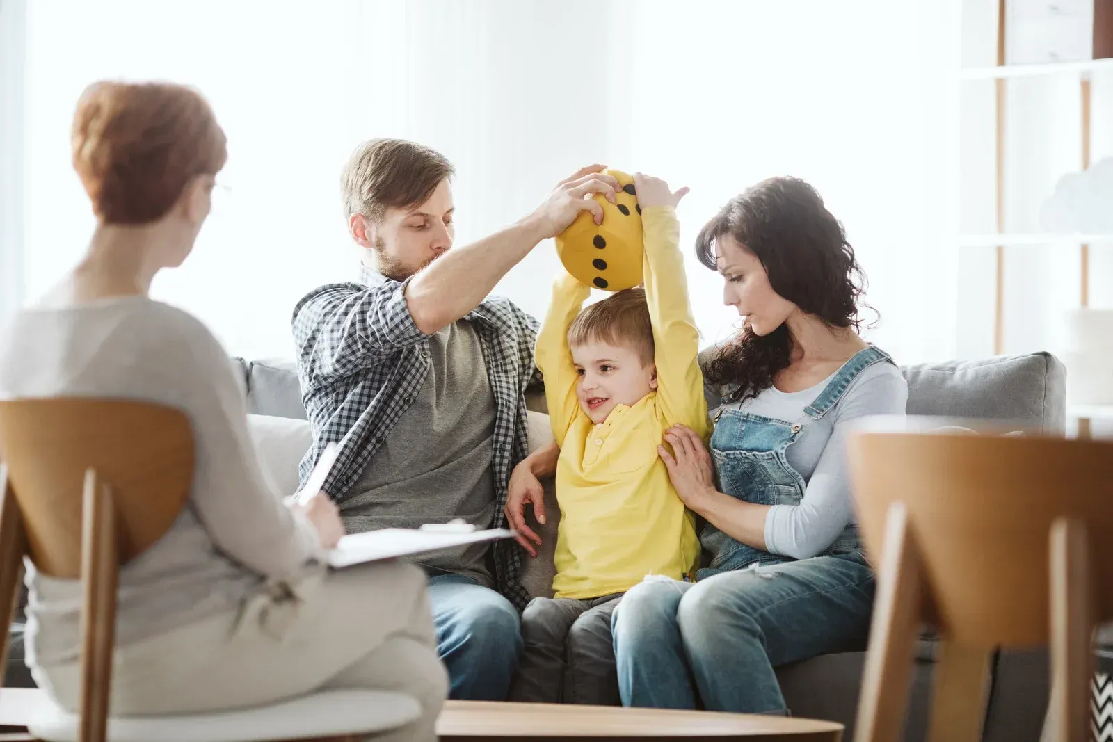 A family is sitting on a couch talking to a counselor.