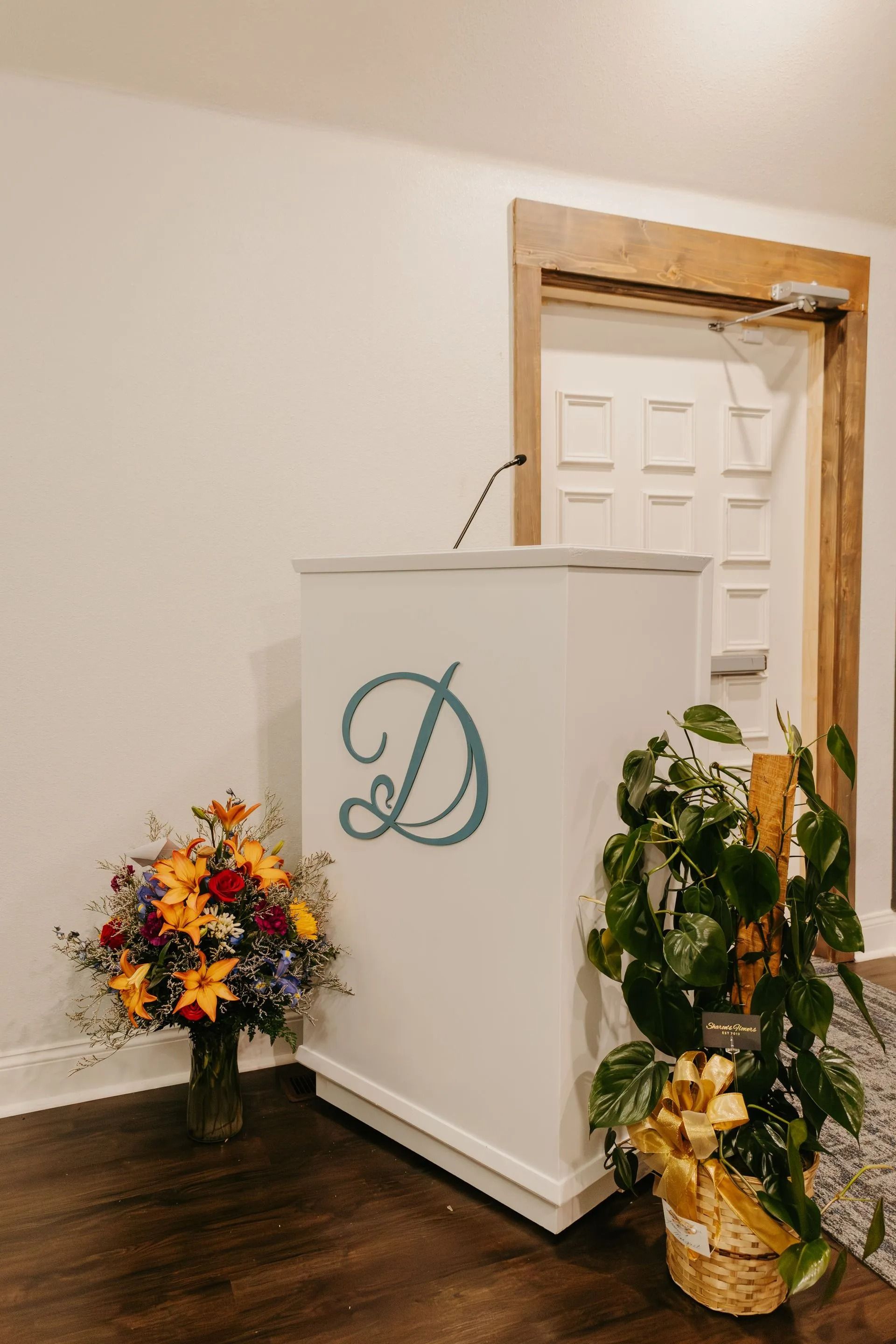 A podium with a letter d on it is next to a vase of flowers.
