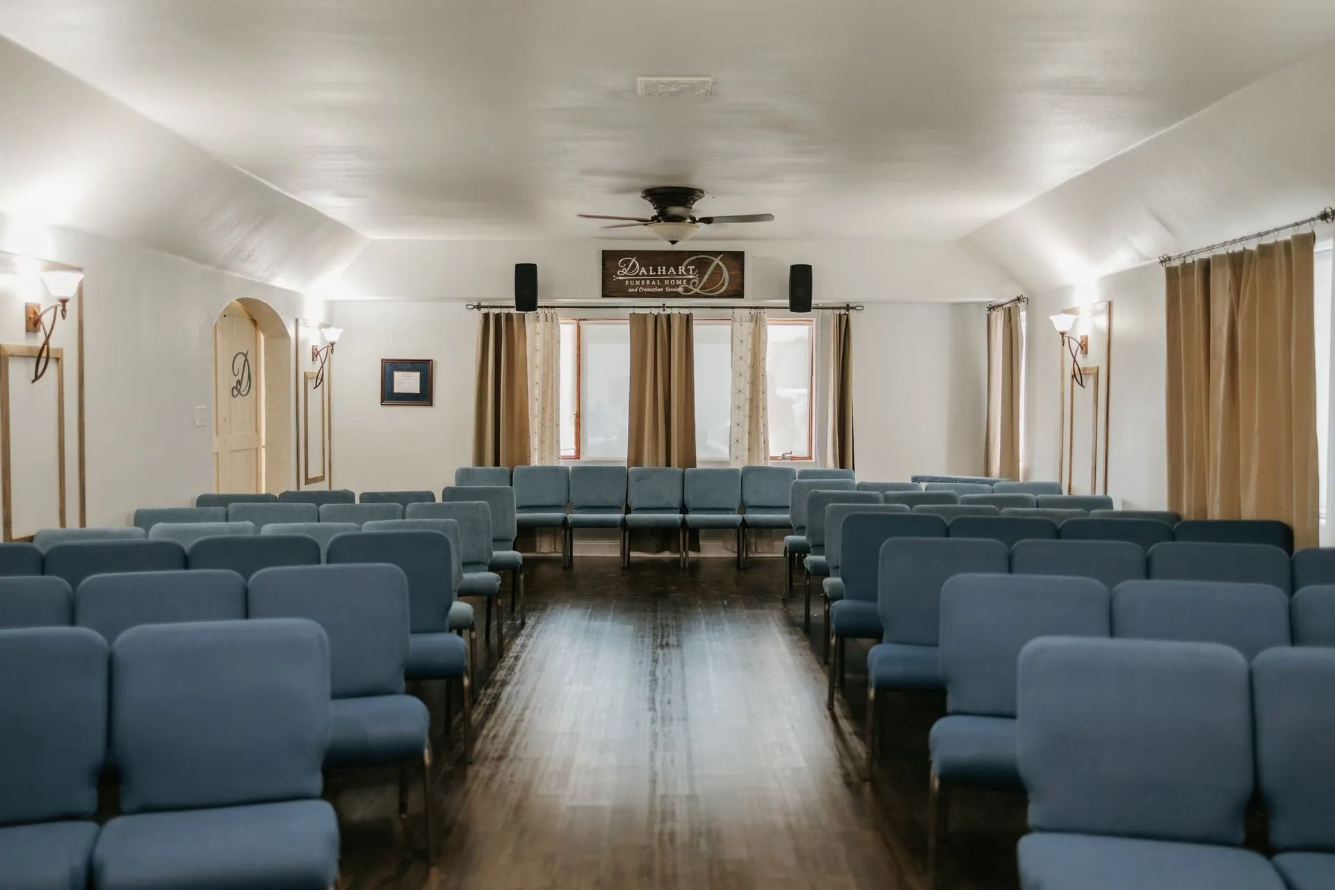 A long row of blue chairs in a room with a wooden floor.