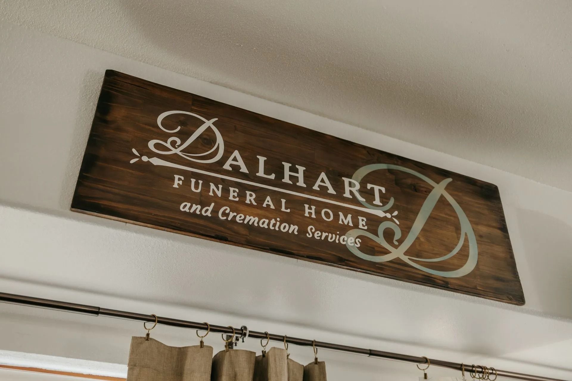 A wooden sign hanging from the ceiling for dalhart funeral home and cremation services.