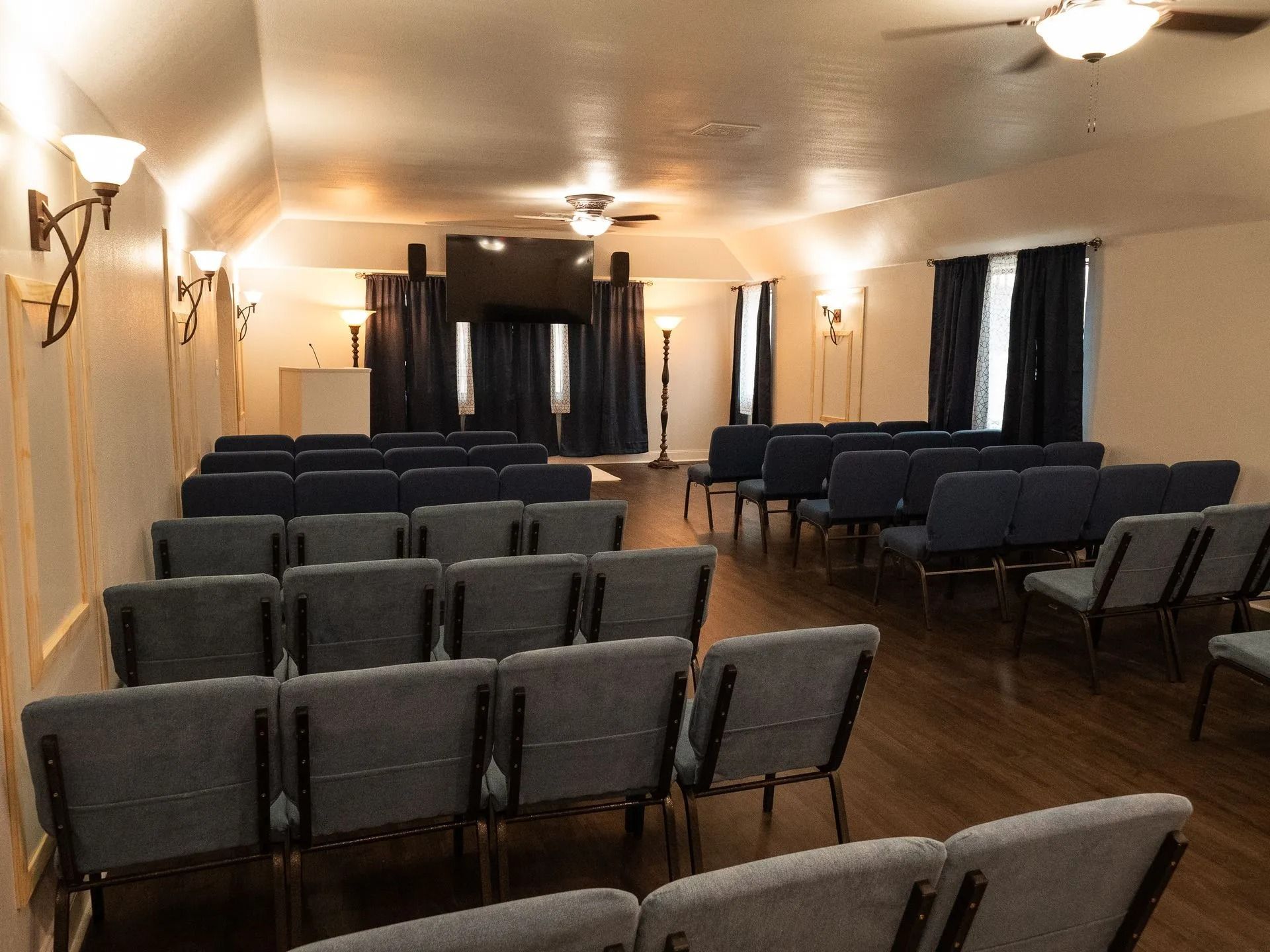 A large room with rows of chairs and a ceiling fan.