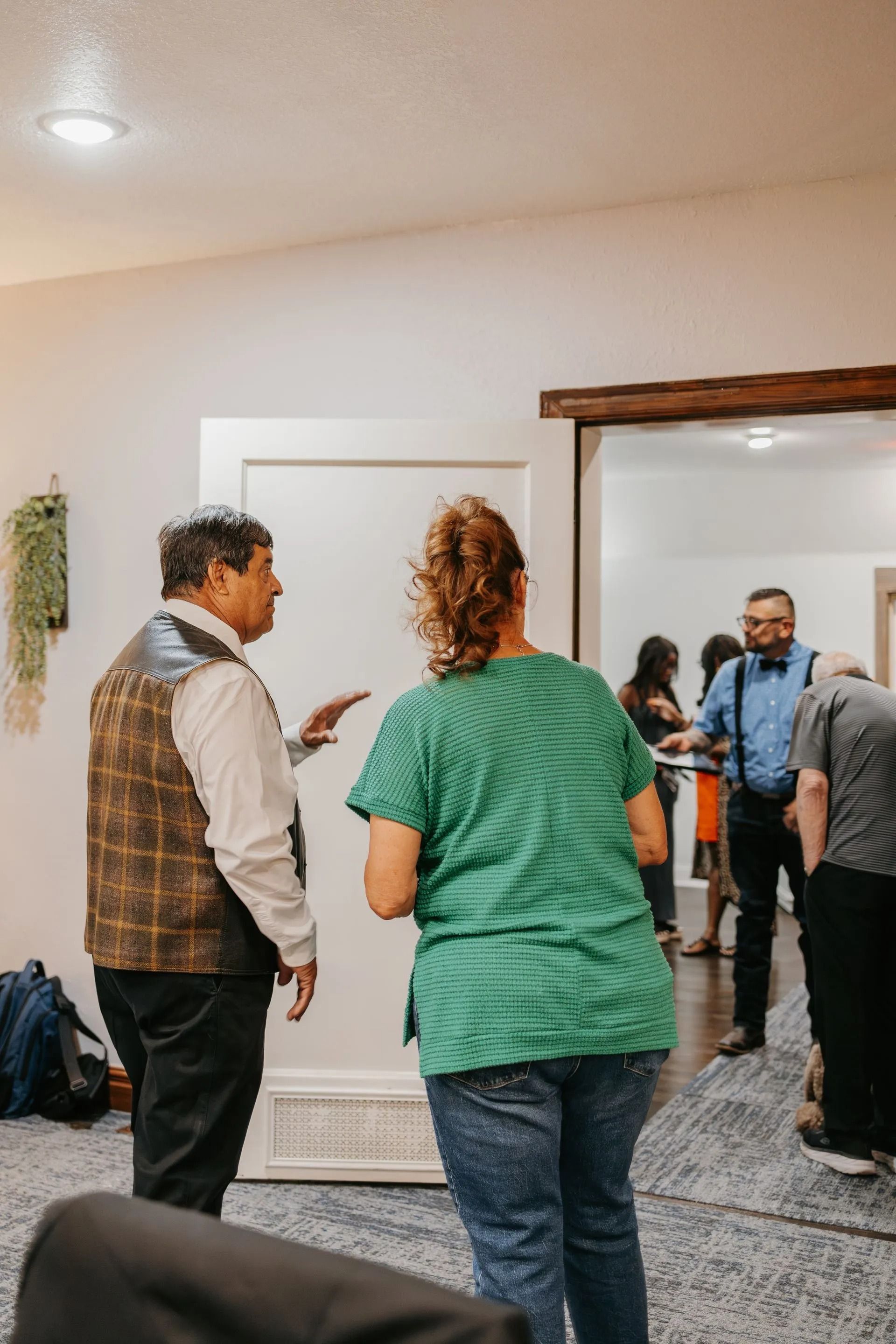 A group of people are standing in a living room talking to each other.