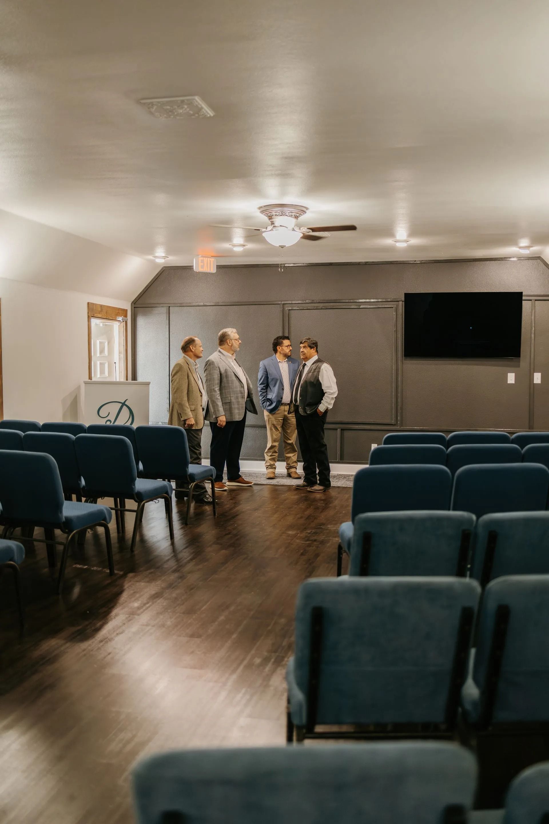 A group of people are standing in a room with blue chairs.