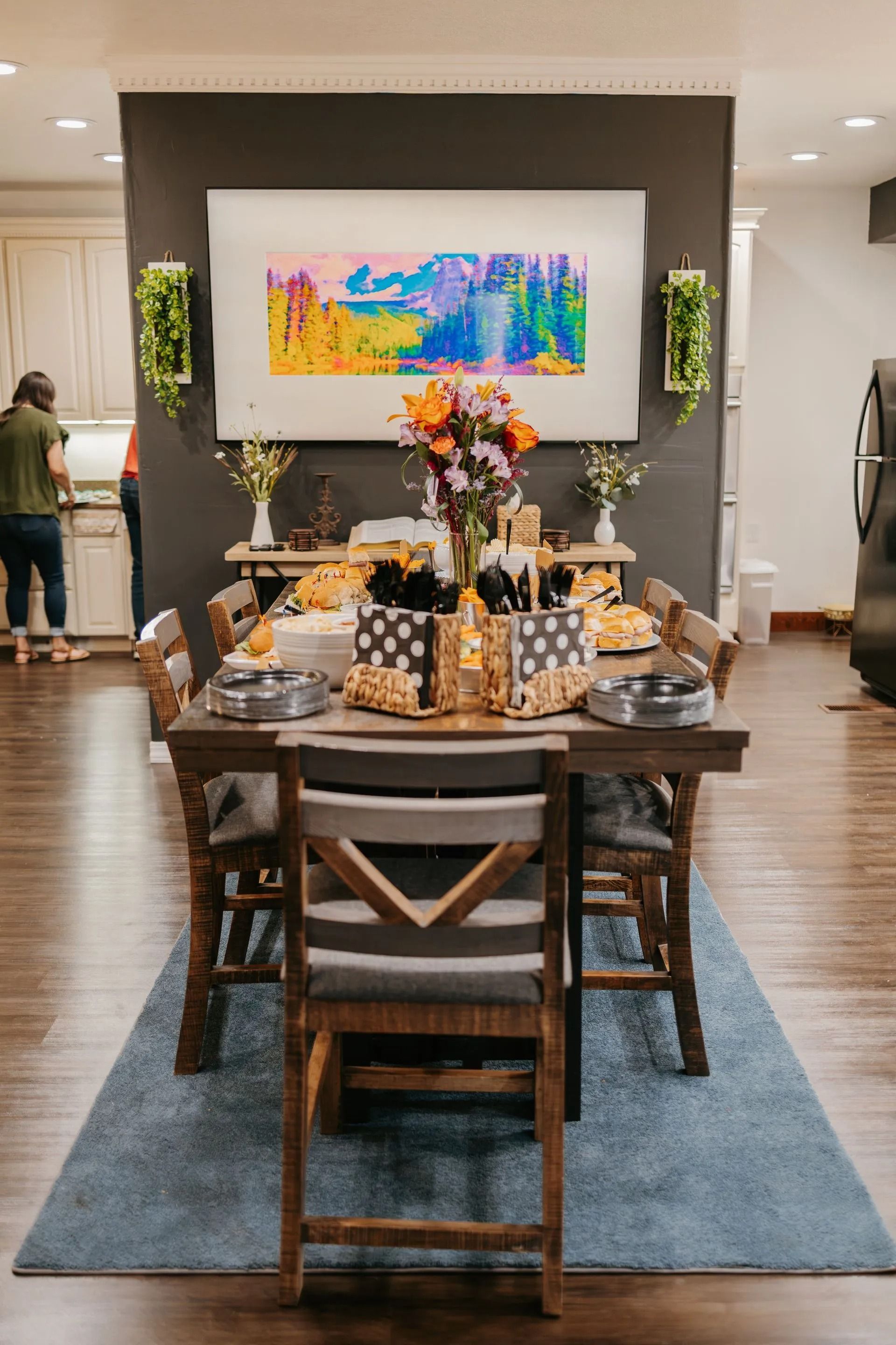 A dining room table with chairs and a painting on the wall.