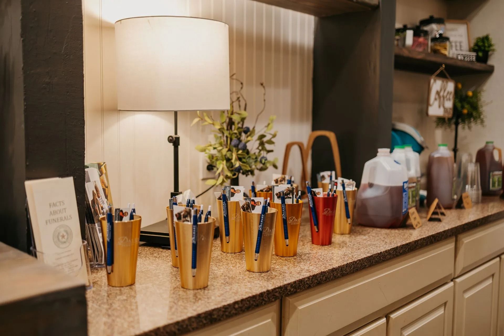 A kitchen counter with a lot of pens and bottles on it.