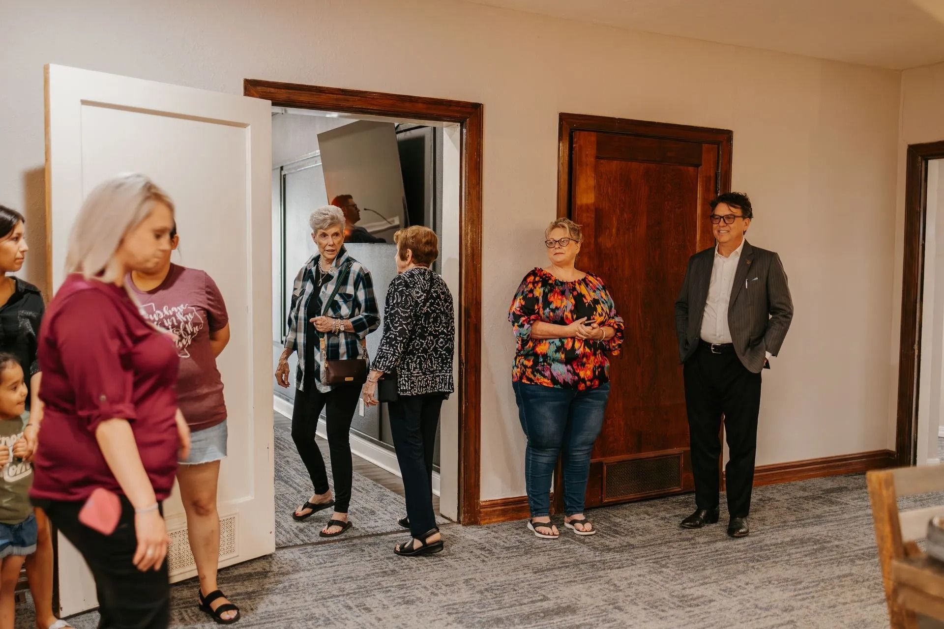 A group of people are standing in a room talking to each other.