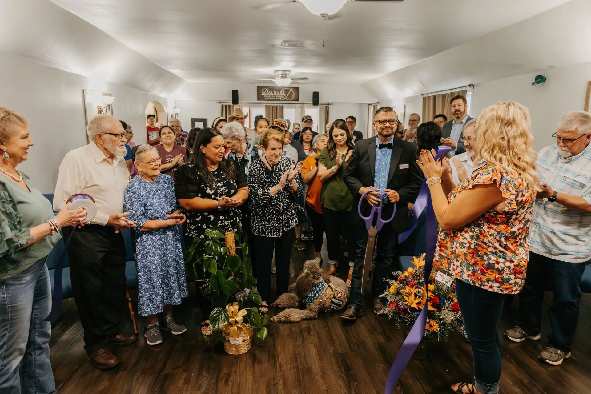 A group of people are standing around a dog in a room.