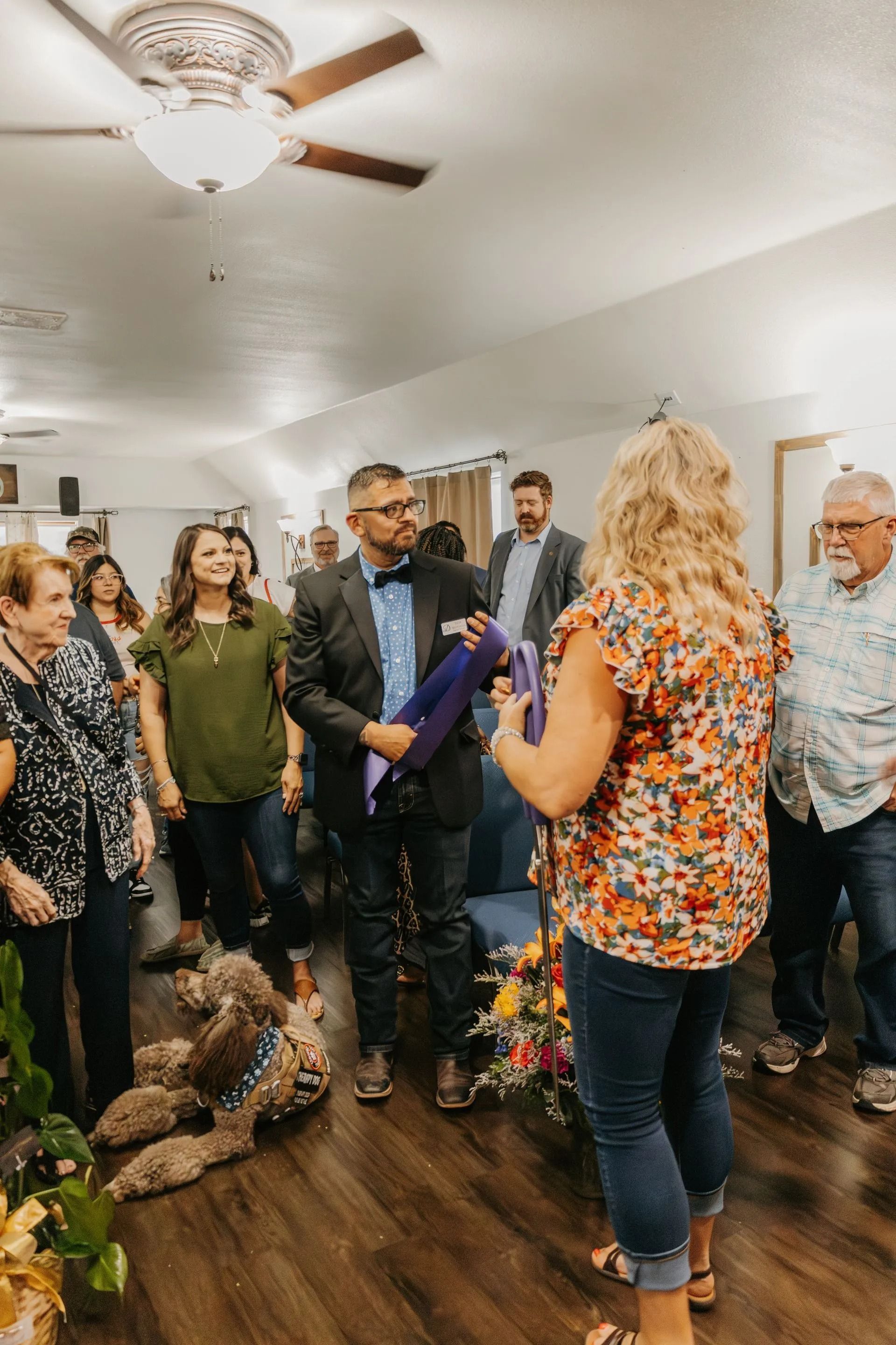 A woman is holding a purple ribbon in front of a group of people.