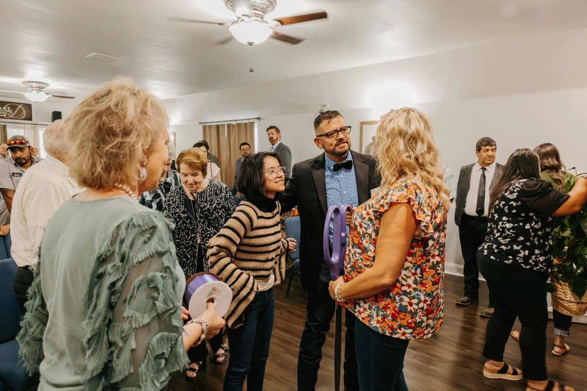 A group of people are standing in a room talking to each other.