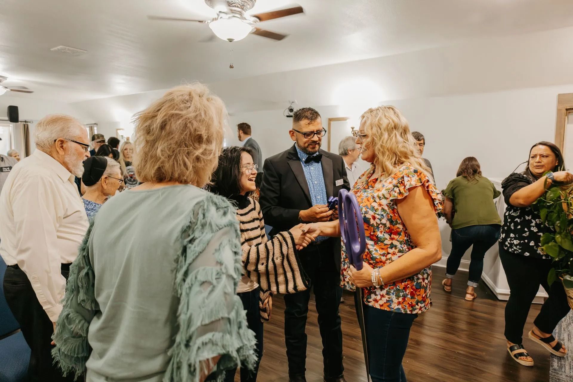 A group of people are standing in a room talking to each other.