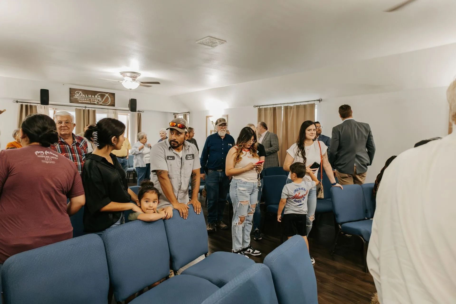 A group of people are standing in a room with blue chairs.