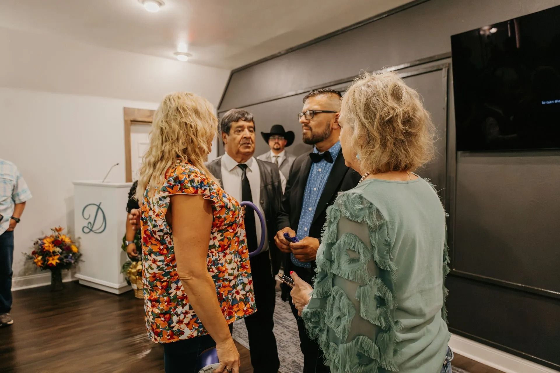 A group of people are standing in a room talking to each other.