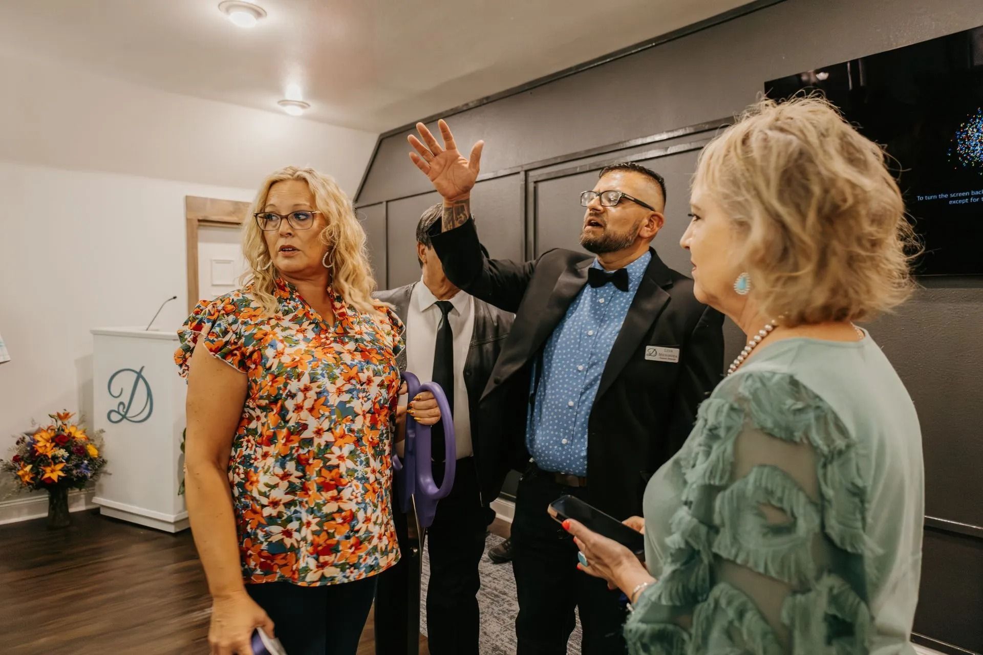 A group of people are standing in a room talking to each other.