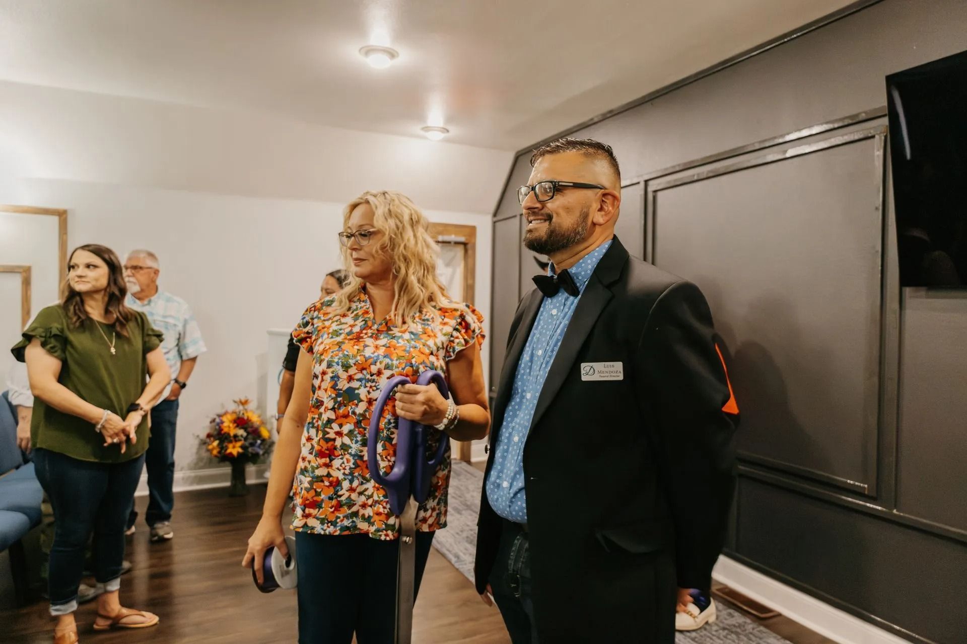 A group of people are standing in a room talking to each other.