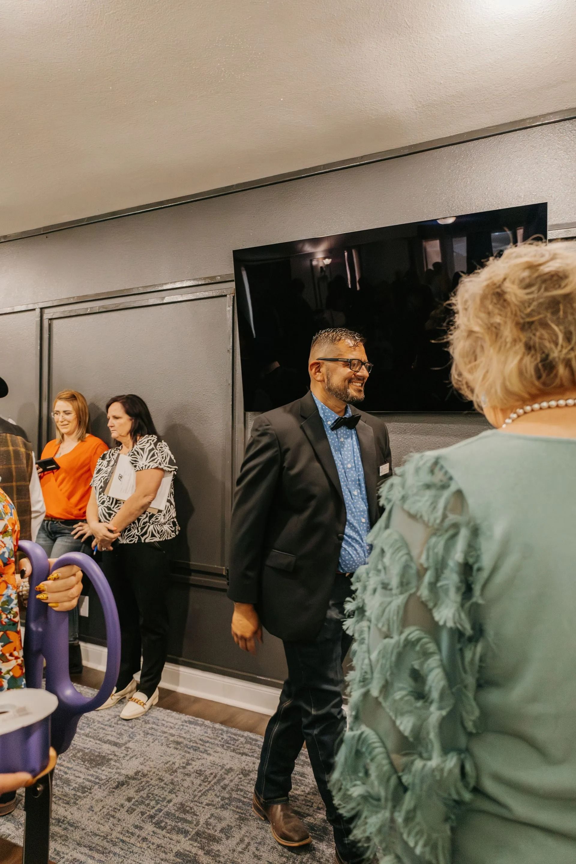 A group of people are standing in a room talking to each other.