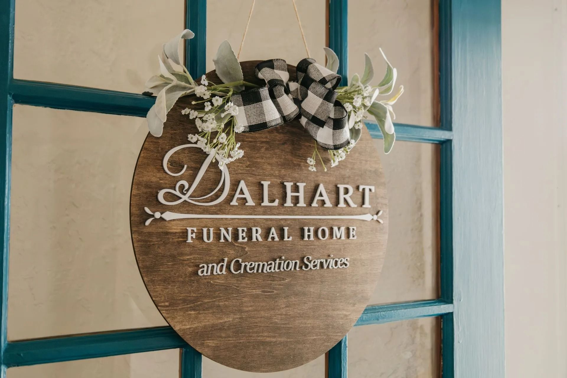 A wooden sign is hanging on a blue door for a funeral home.