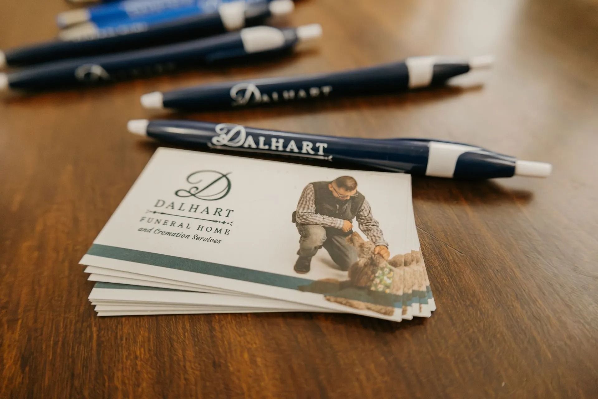 A stack of business cards and pens on a wooden table.