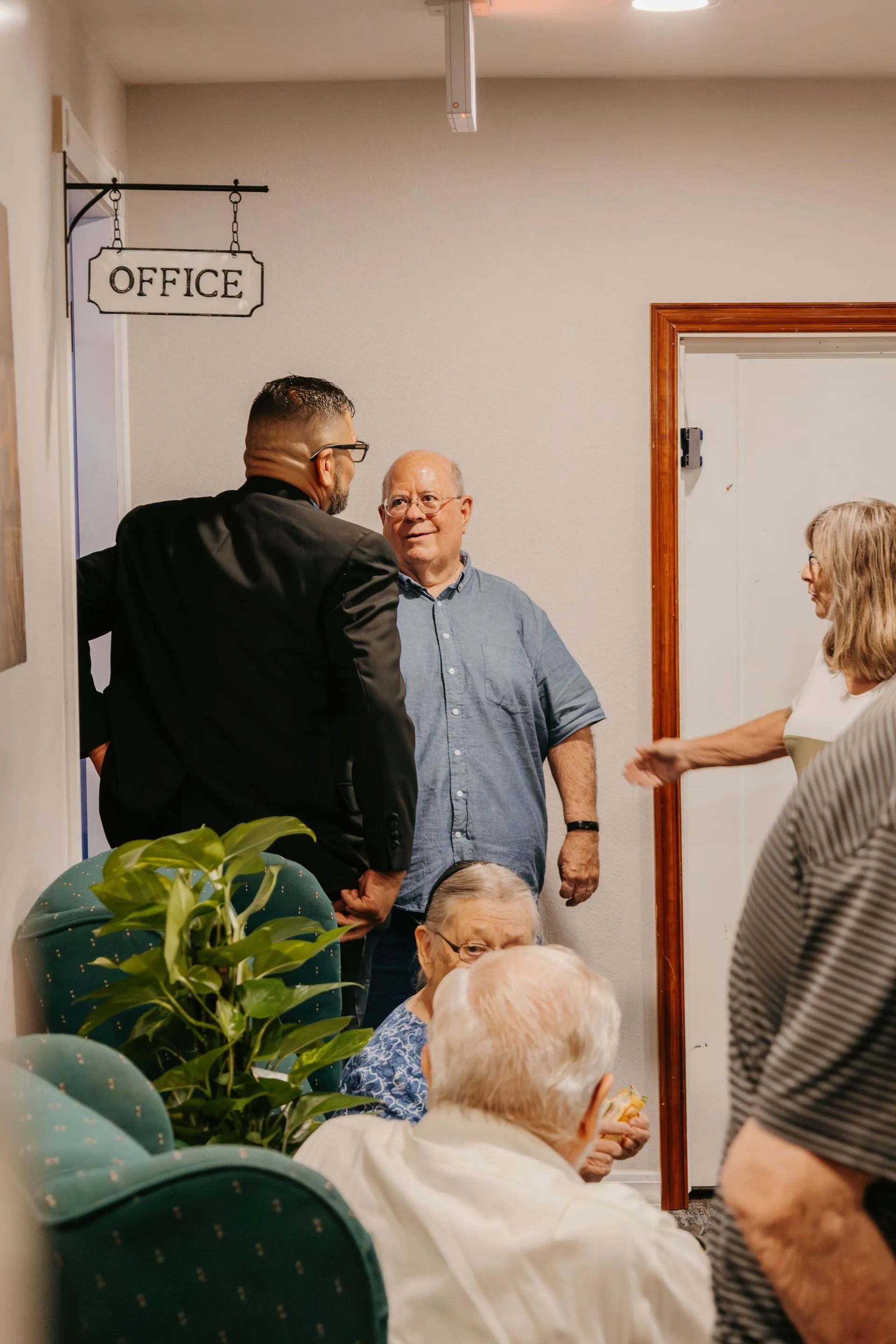 A group of people are standing in a hallway talking to each other.