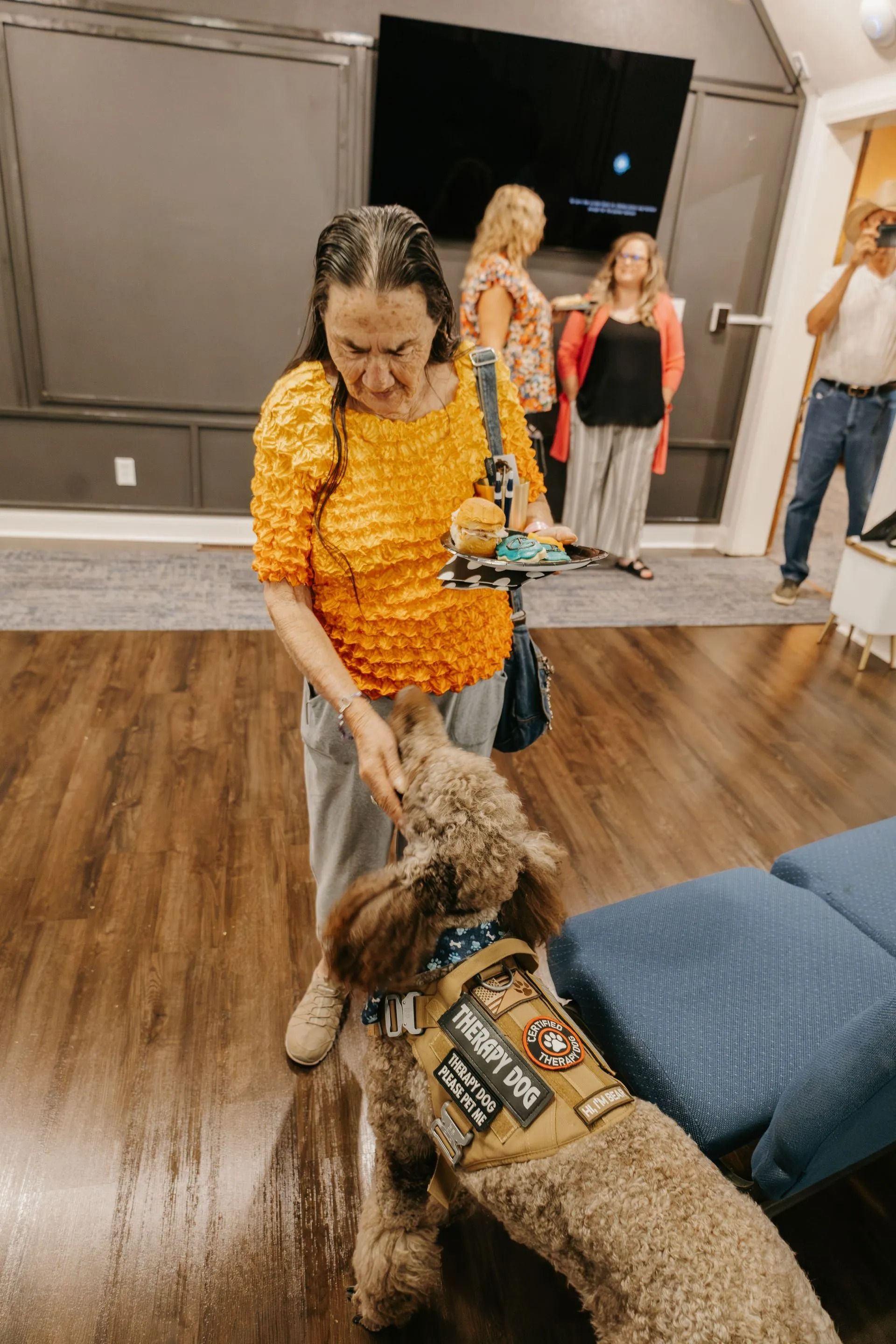 A woman is standing next to a dog wearing a service dog vest.