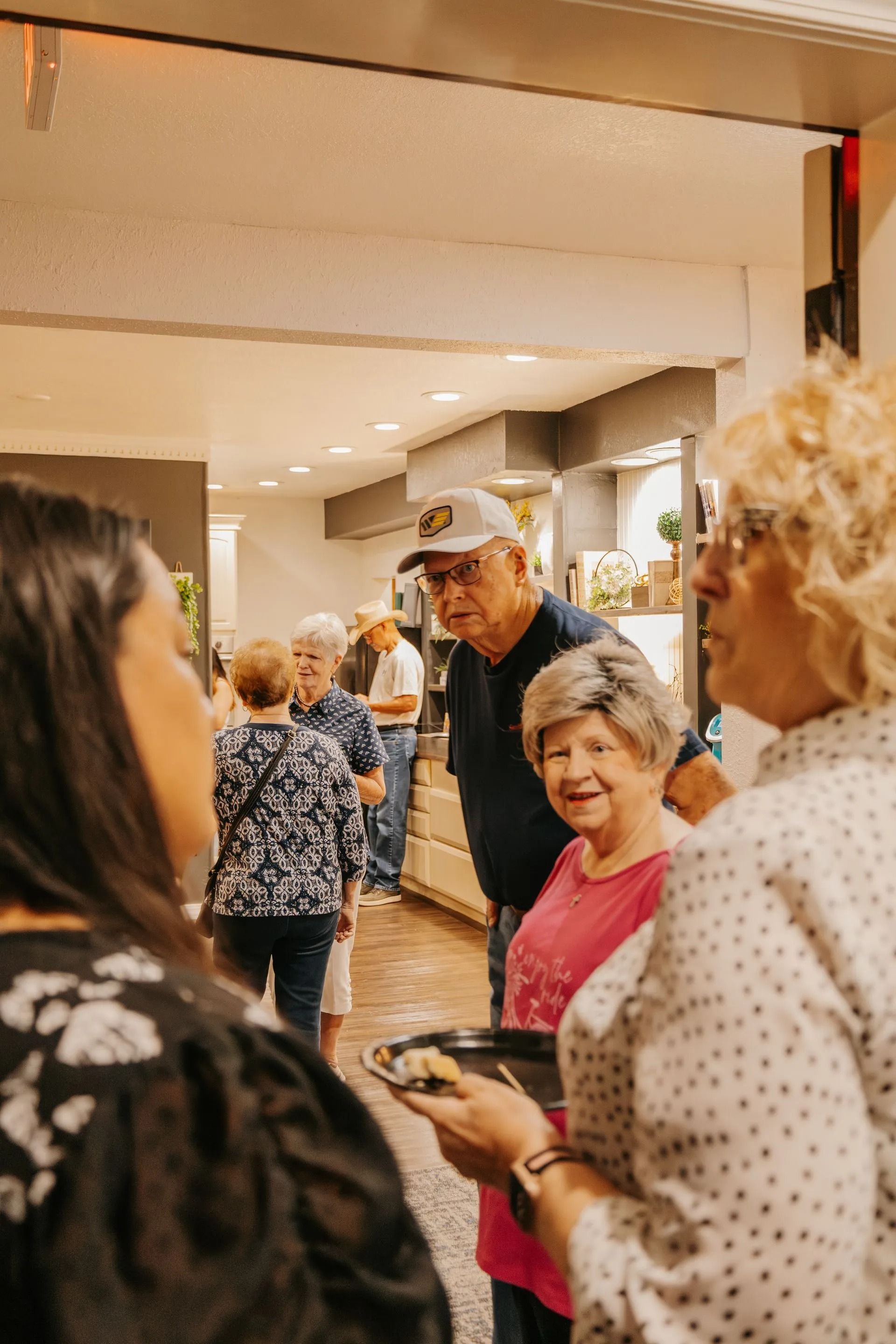 A group of people are standing in a room talking to each other.