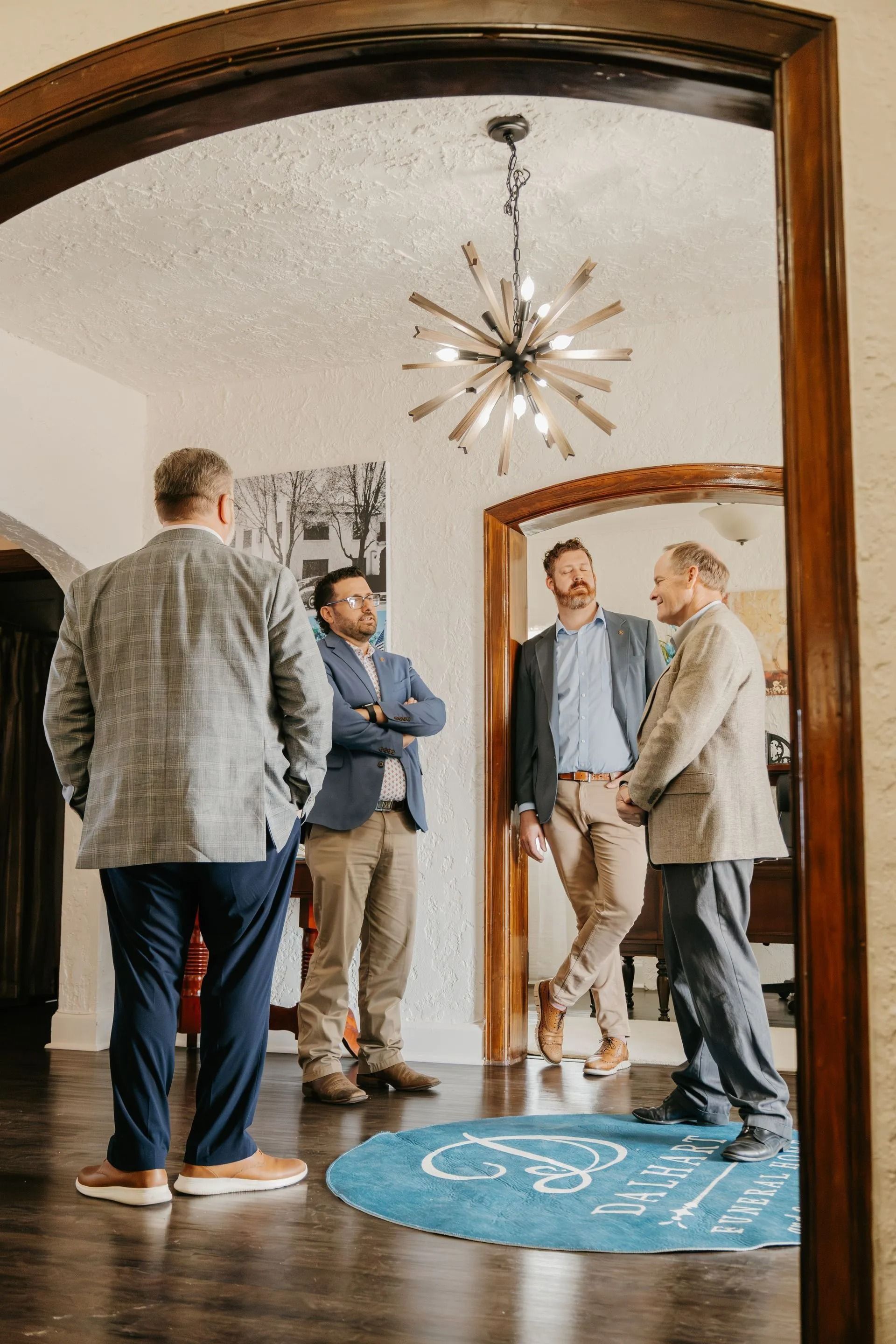 A group of men are standing in a room talking to each other.