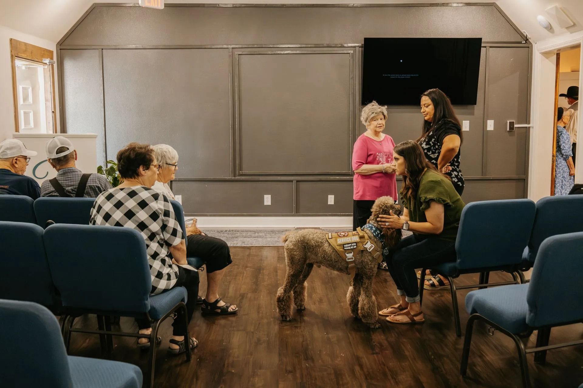 A group of people are sitting in chairs in a room with a dog.