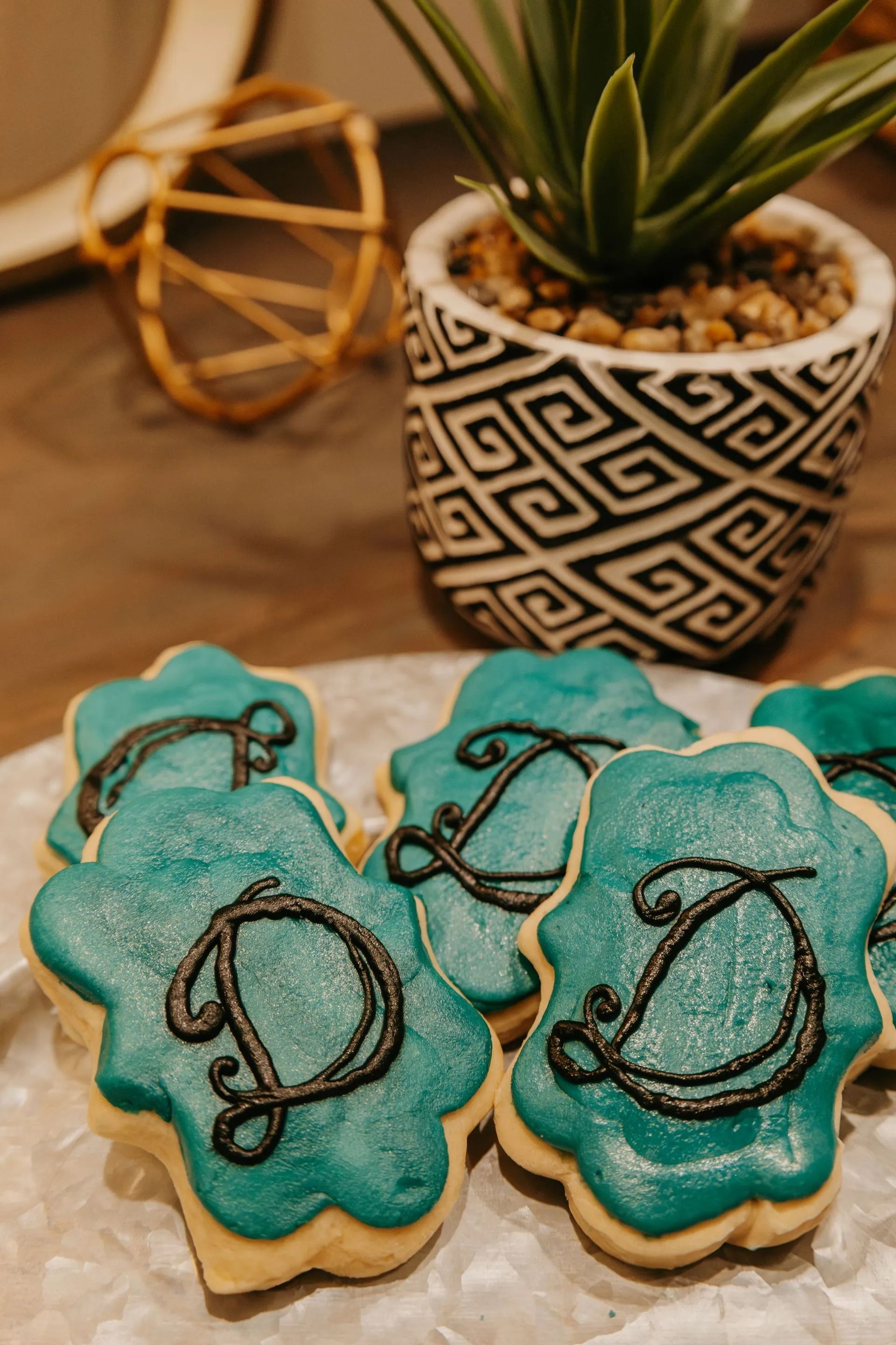 A bunch of cookies with the letter d on them are sitting on a table next to a potted plant.