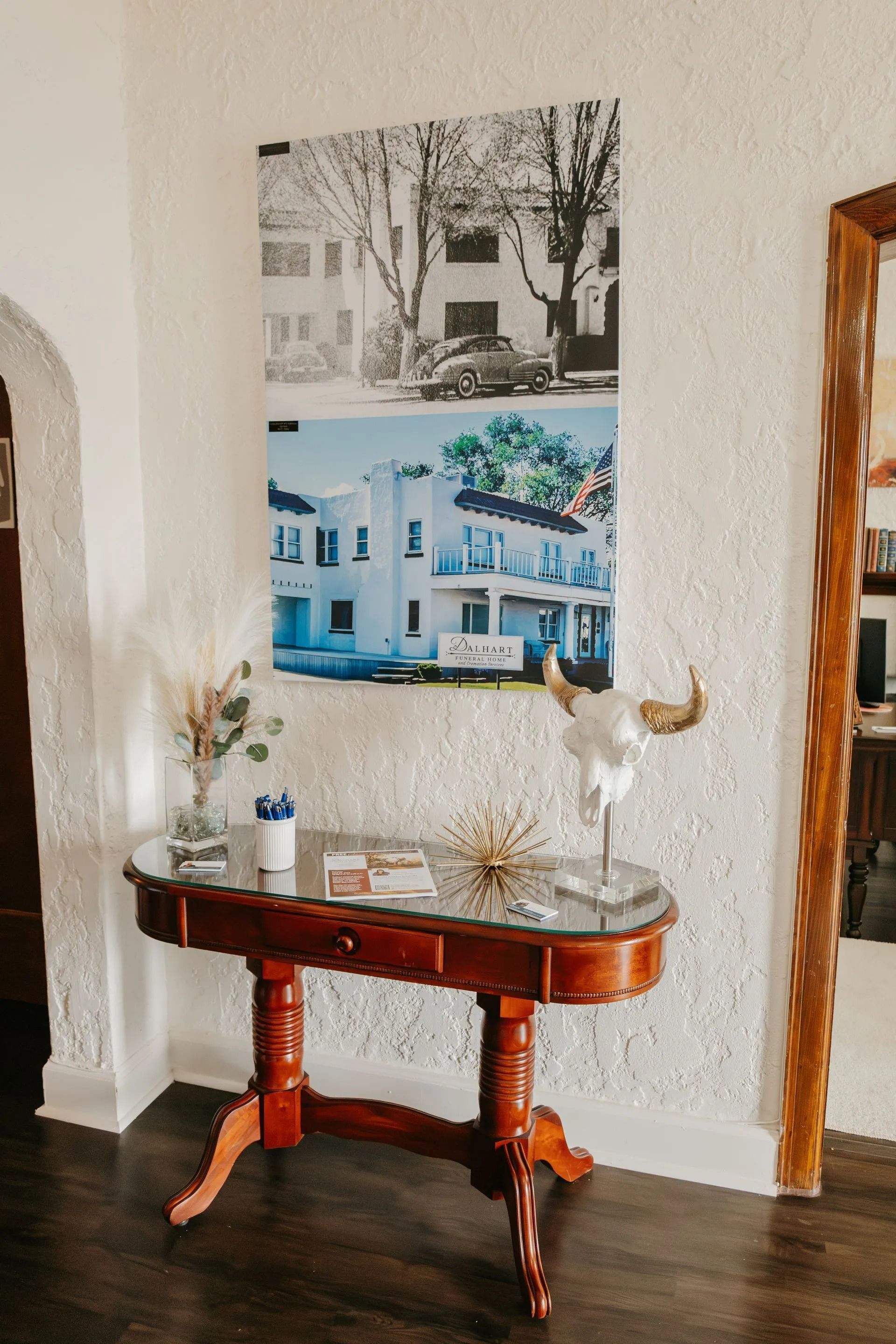 A table with a picture of a house on the wall above it.