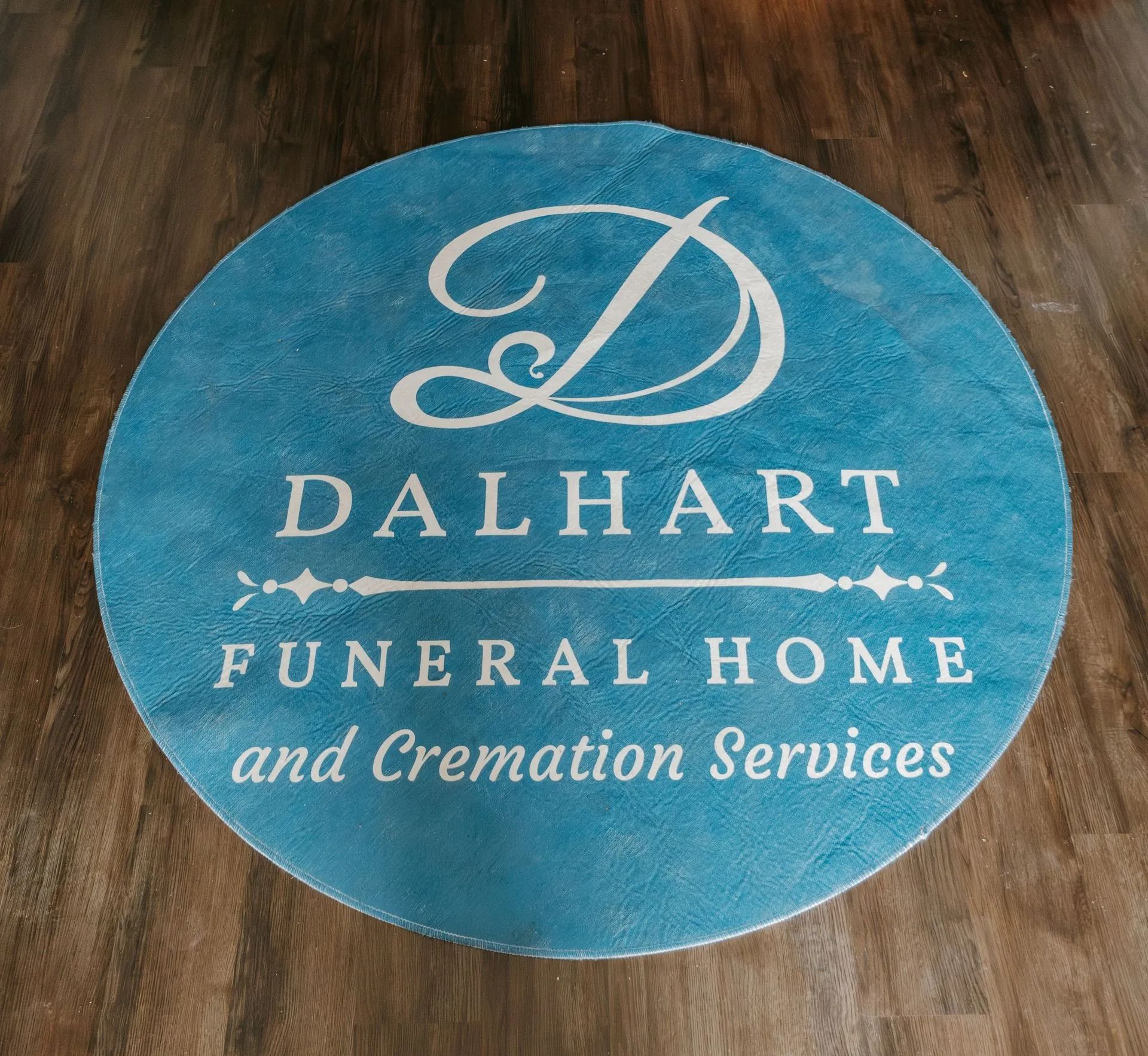 A blue rug with the dalhart funeral home and cremation services logo on it