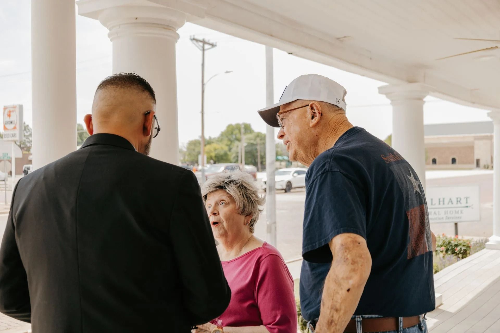A group of people are standing next to each other on a porch talking to each other.
