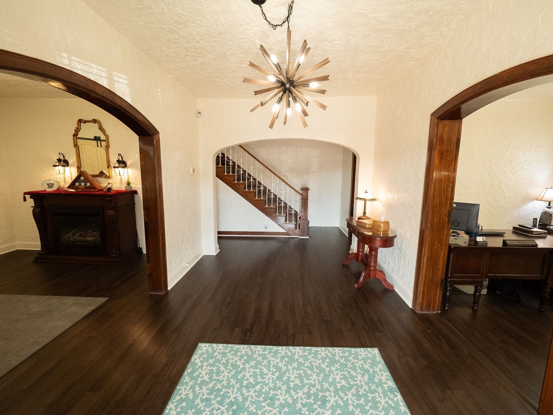 A hallway in a house with a fireplace and stairs