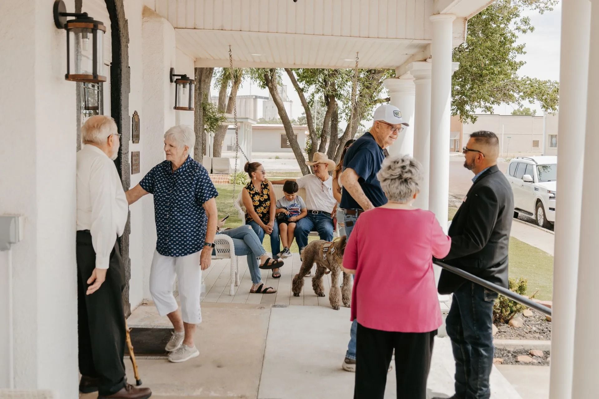 A group of people are standing on a porch talking to each other.