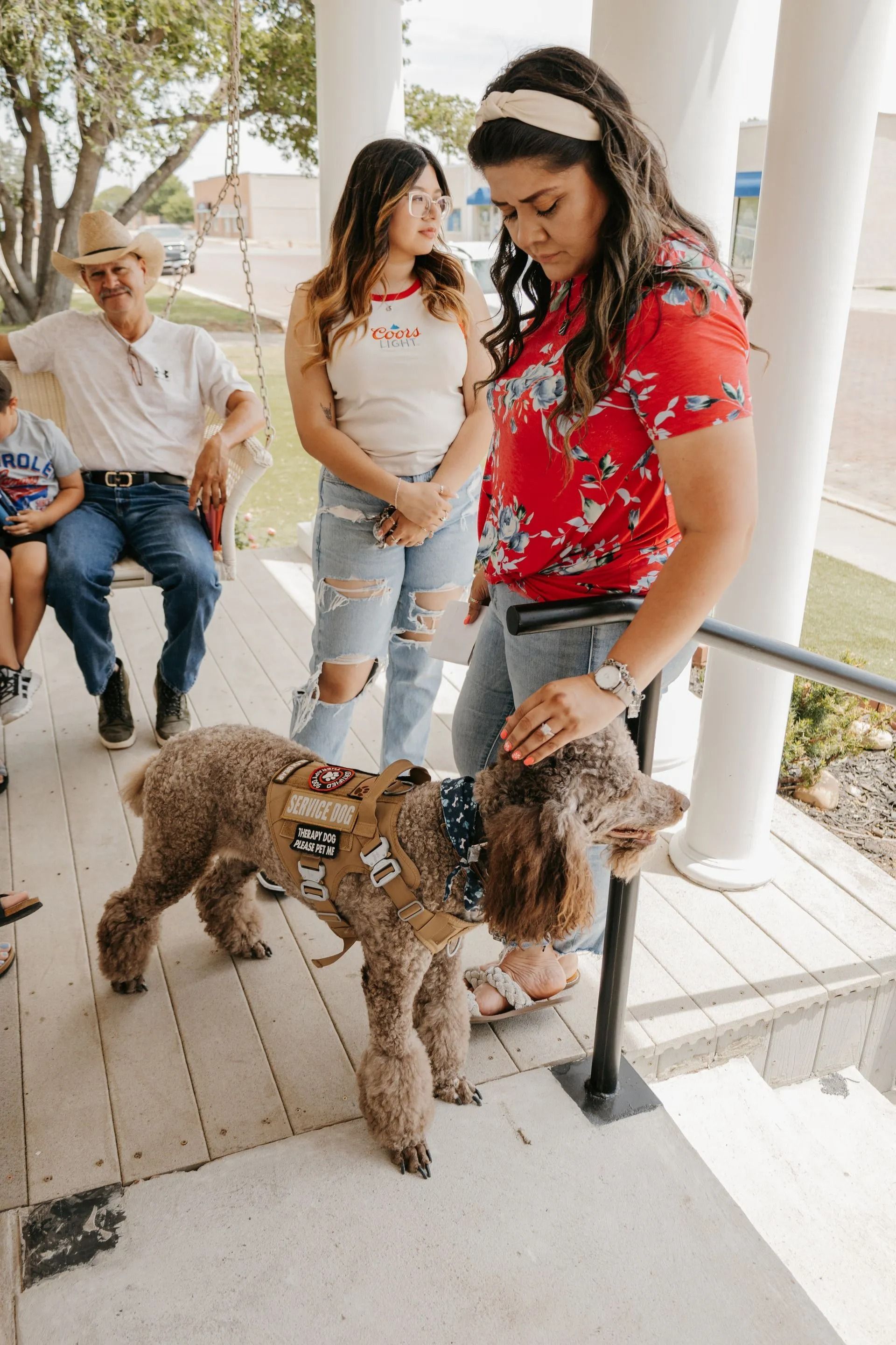 A woman is petting a small dog on a porch.