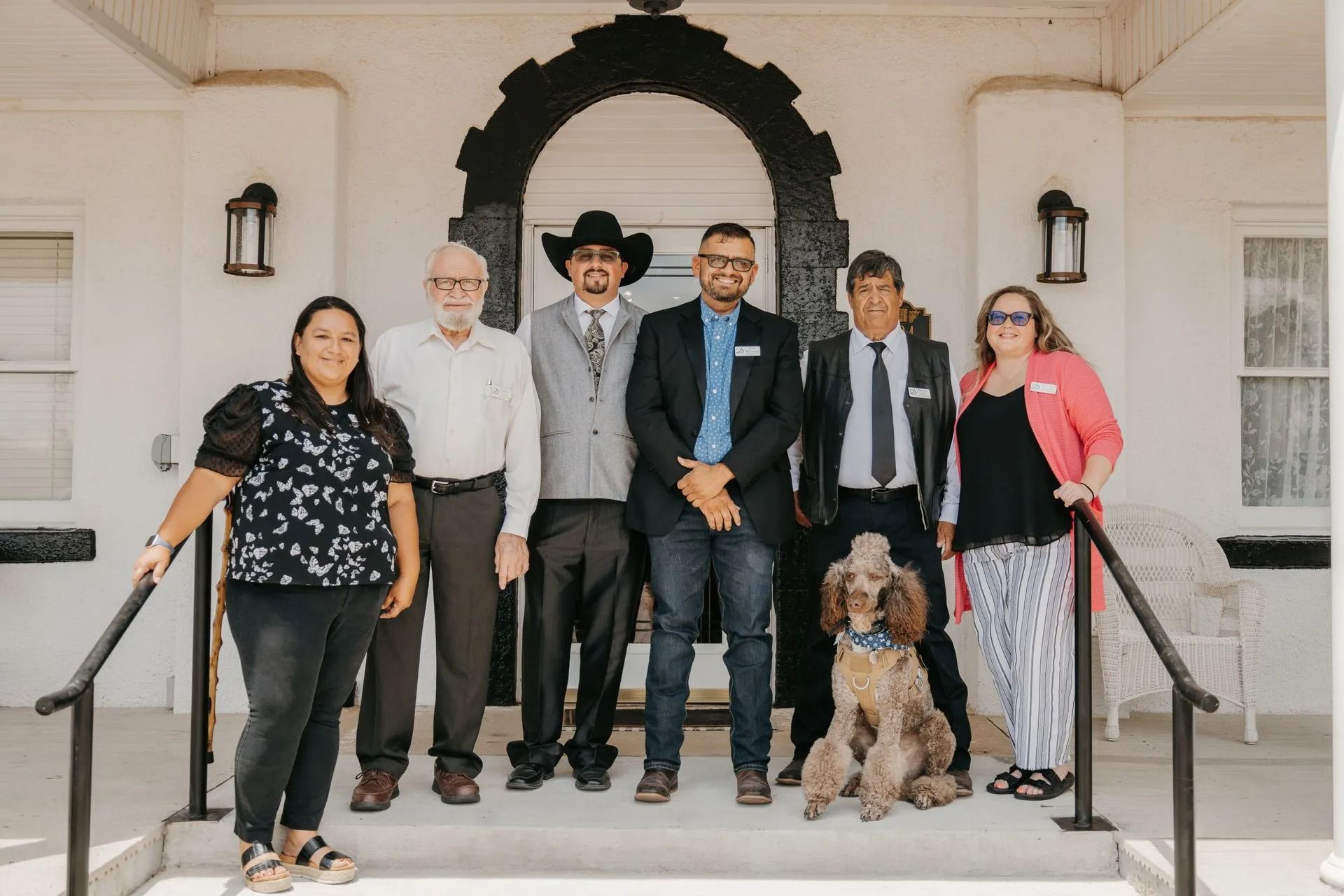 A group of people standing on the steps of a building with a dog.