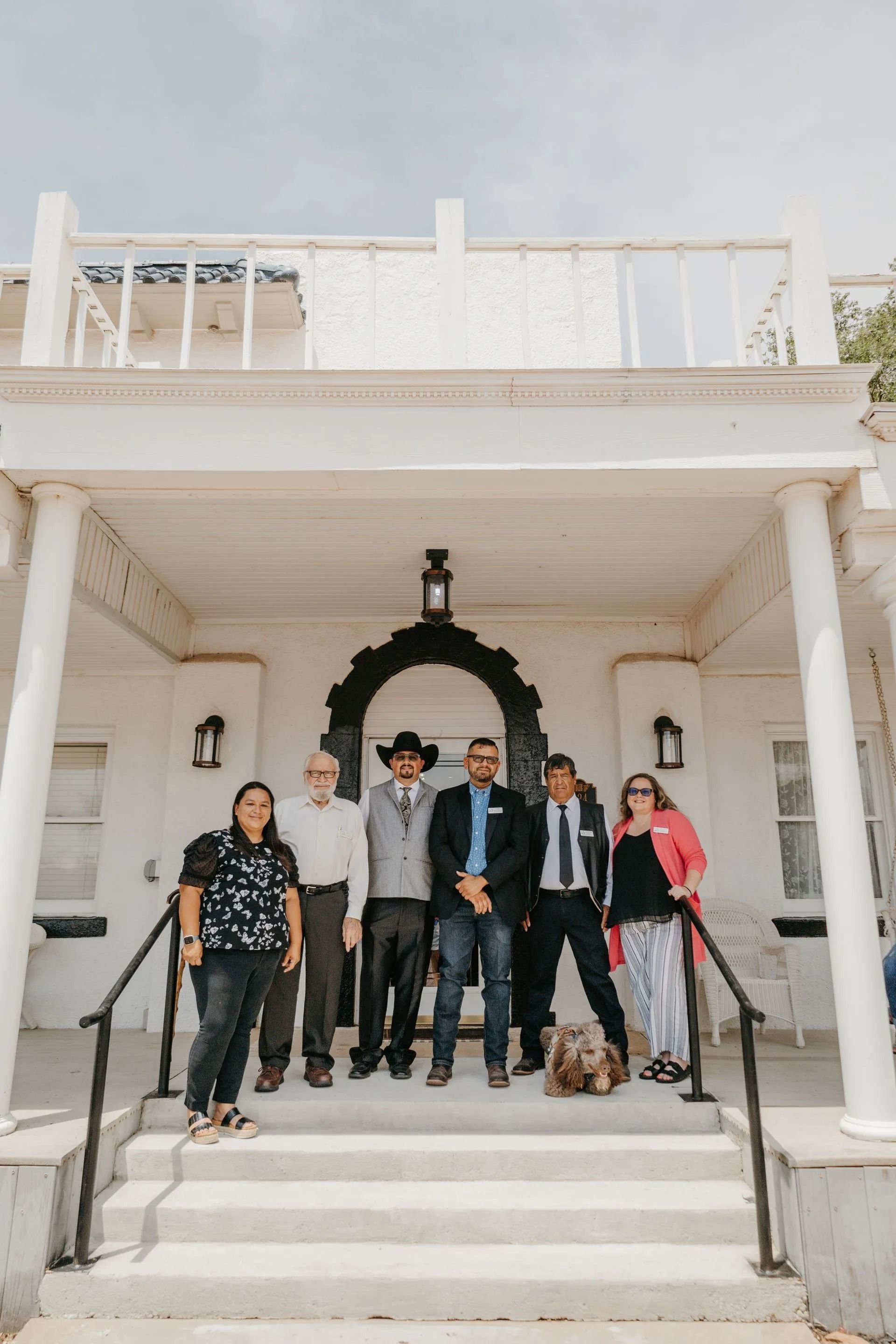 A group of people are standing on the steps of a building.