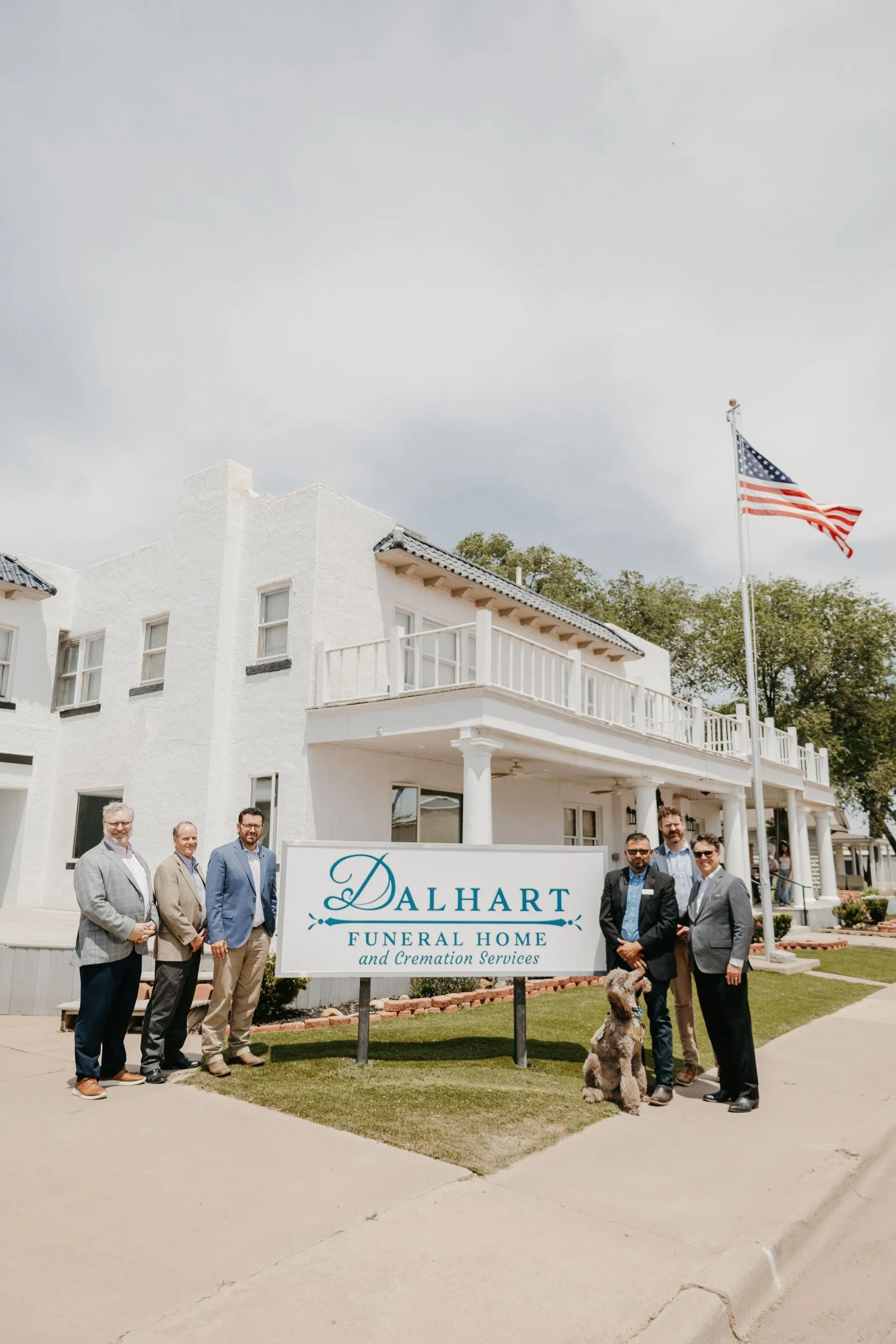 A group of men are standing in front of a white building.