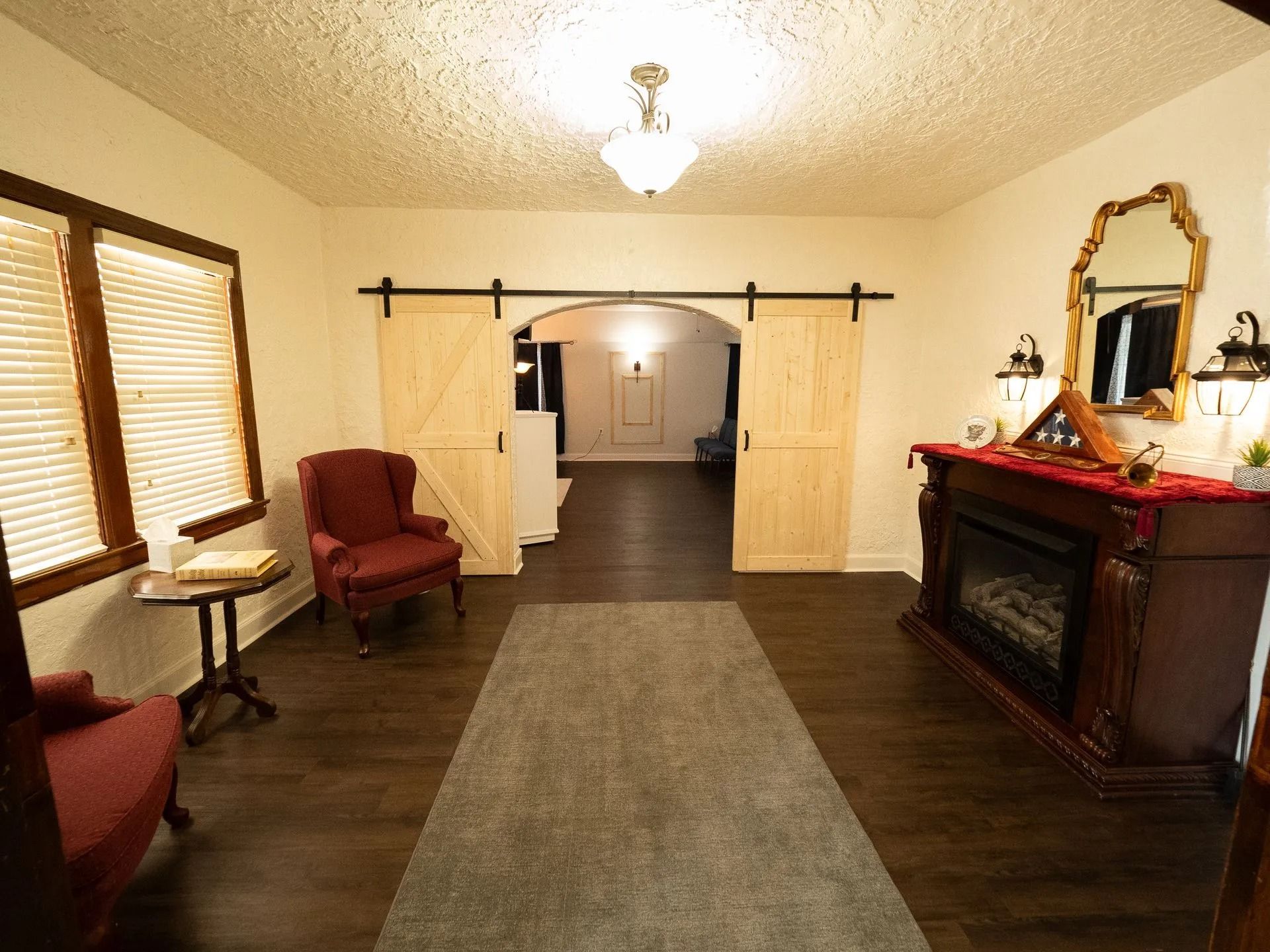 A living room with a fireplace , chairs , and a mirror.
