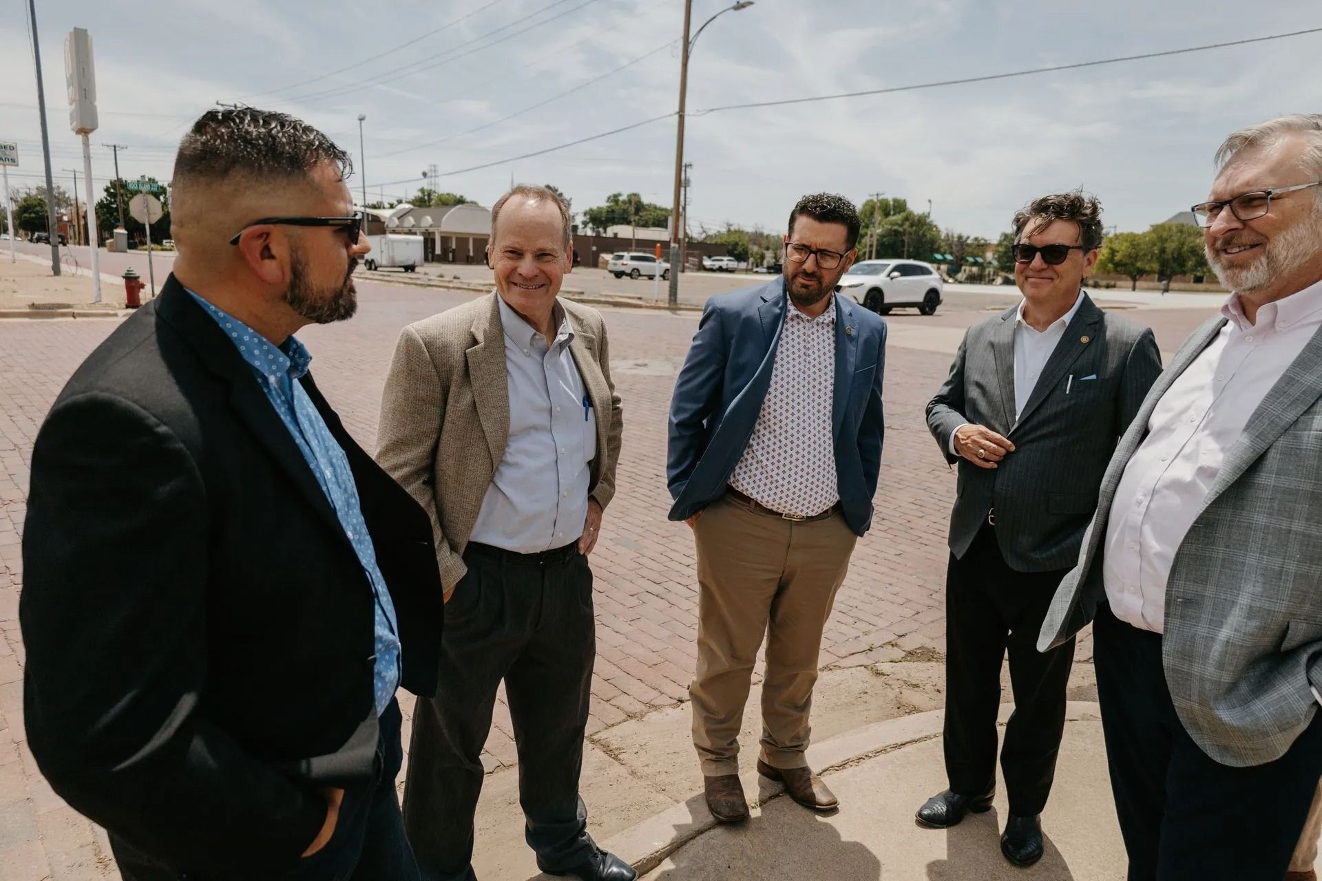 A group of men in suits are standing next to each other on a sidewalk.