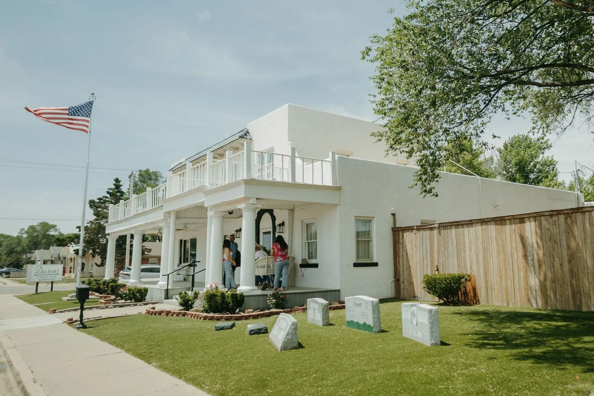 A white house with a cemetery in front of it.